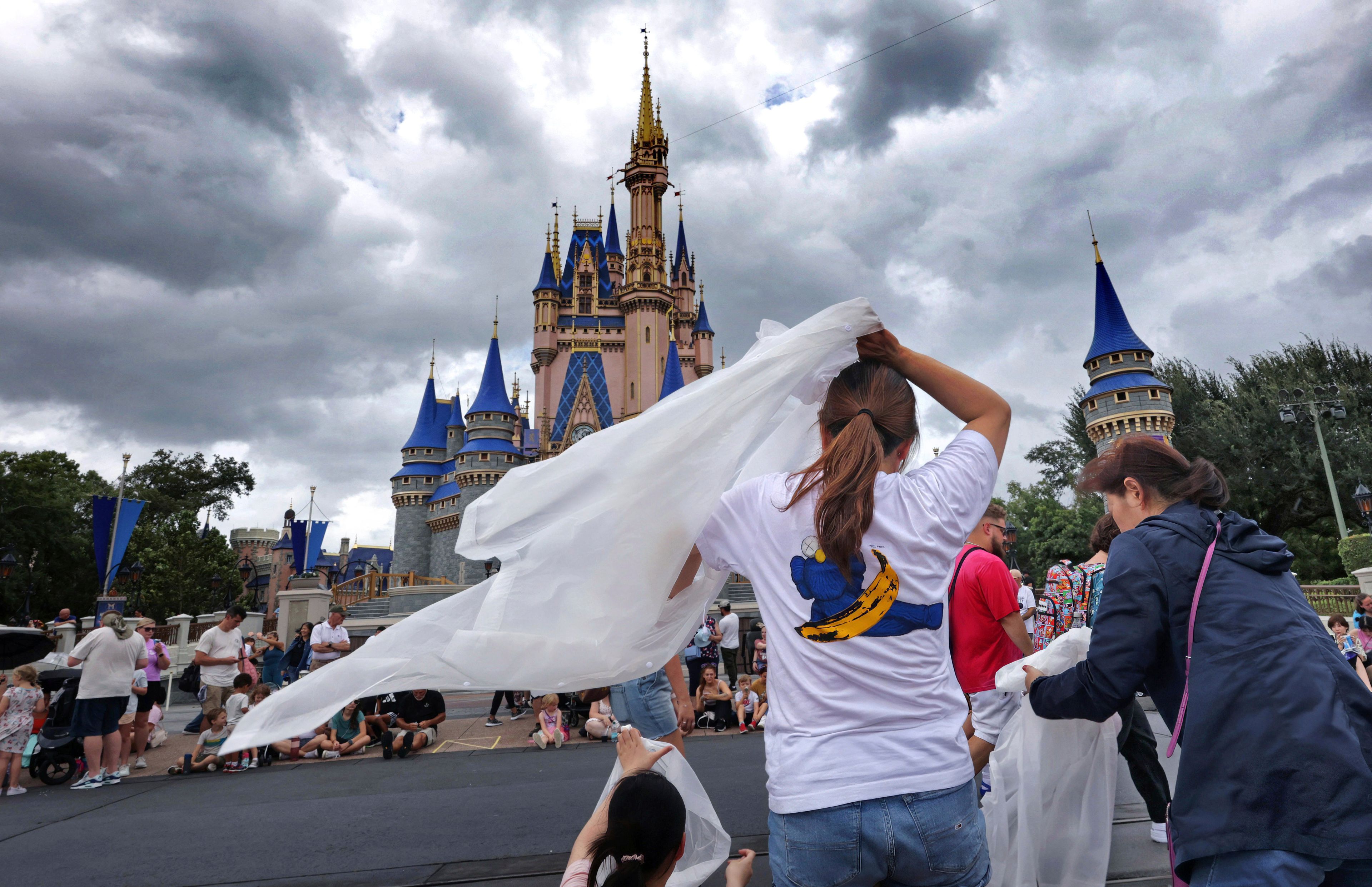 Guests at the Magic Kingdom break out ponchos at Cinderella Castle as bands of weather from Hurricane Helene move through Walt Disney World in Bay Lake, Fla., Thursday, Sept. 26, 2024. All four of Disney's Florida theme parks remained open Thursday as the storm passed to the west in the Gulf of Mexico. (Joe Burbank/Orlando Sentinel via AP)