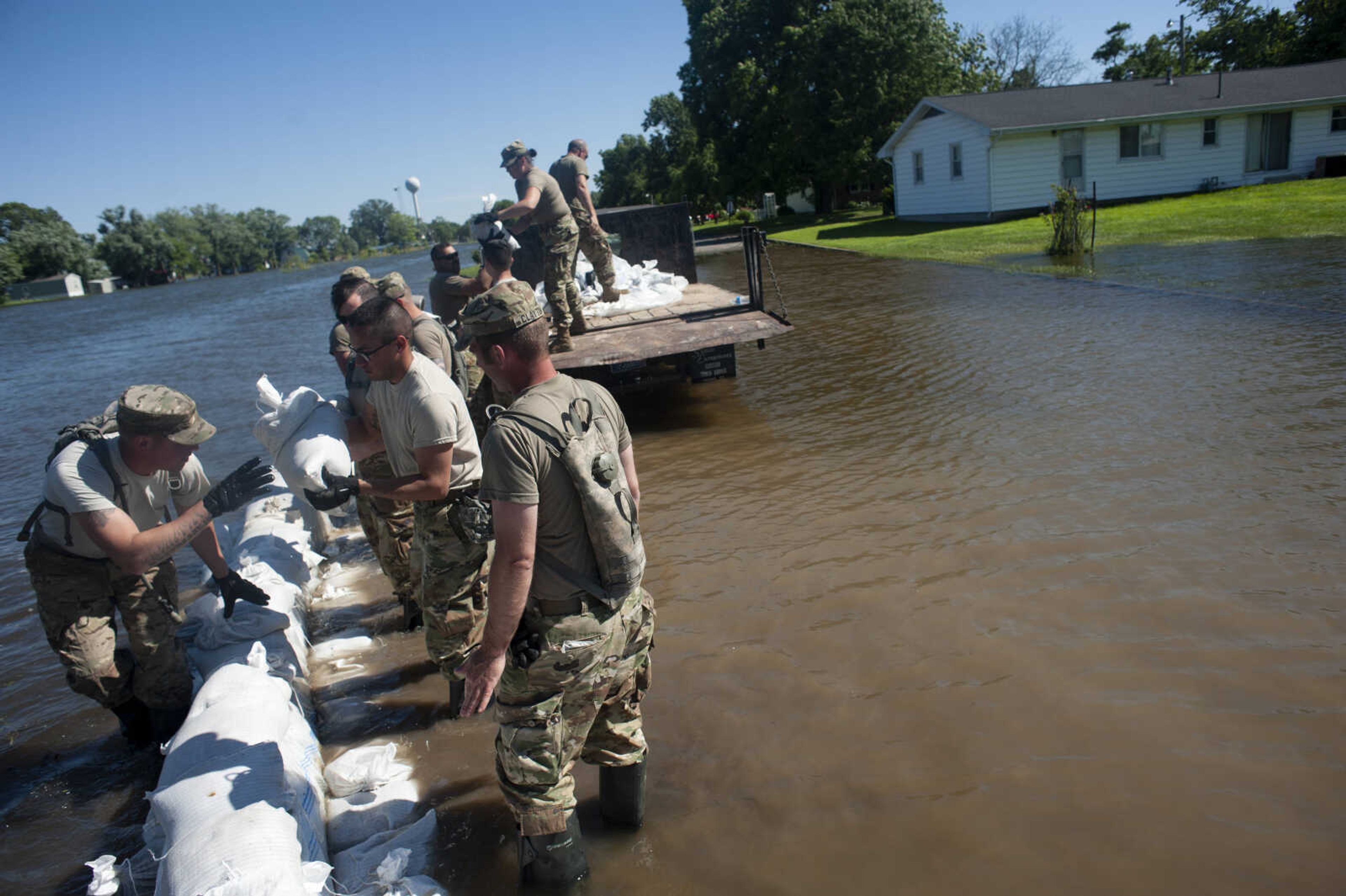 Members of the Illinois National Guard build up existing sandbag barriers to hold back floodwaters Monday, June 10, 2019, along Brookwood Drive in East Cape Girardeau, Illinois.