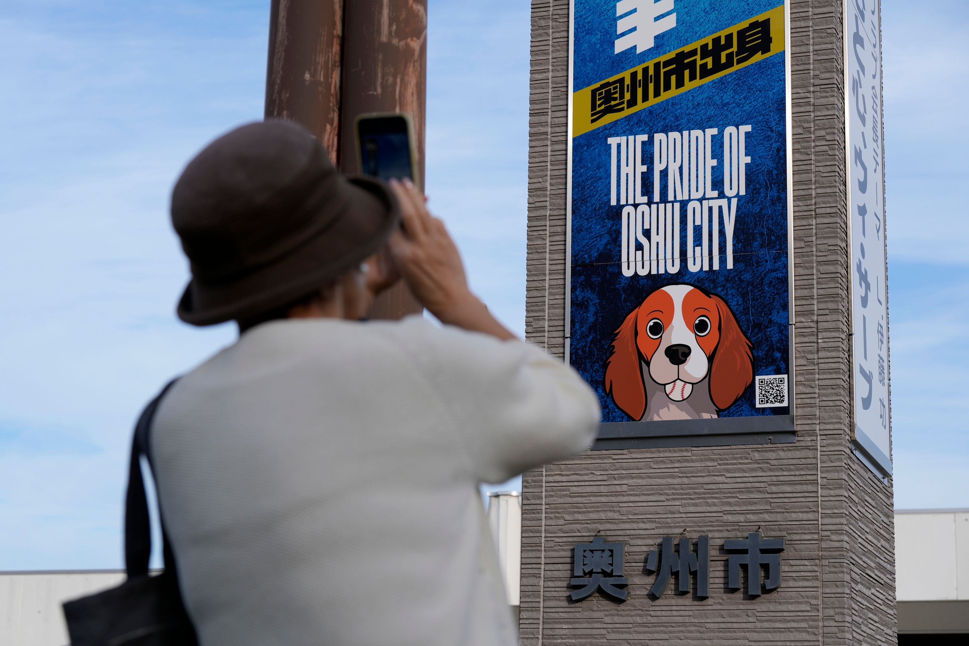 A visitor photographs a banner to support Shohei Ohtani of the Los Angeles Dodgers, near Mizusawa train station in Oshu, northeastern Japan, the hometown of Ohtani, Tuesday, Oct. 29, 2024. (AP Photo/Eugene Hoshiko)