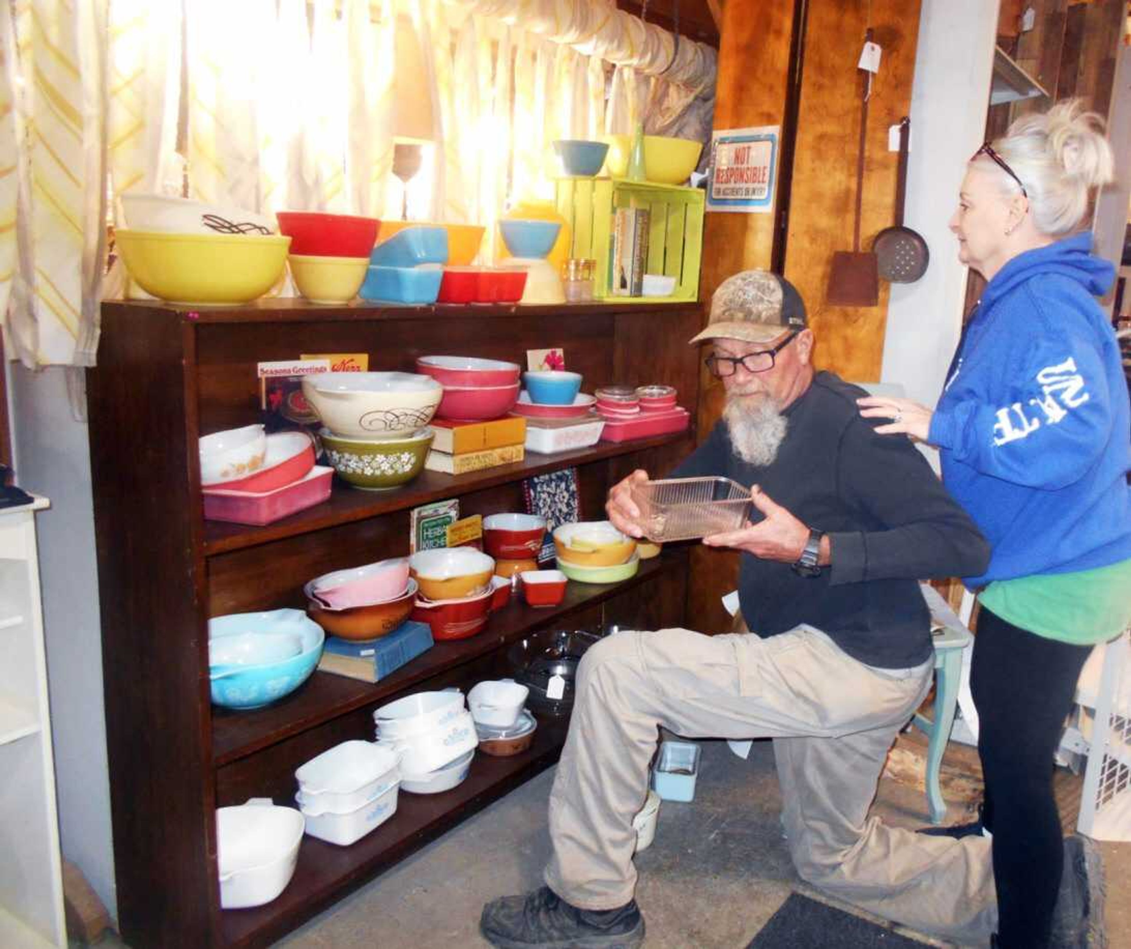 Mike Morris examines a glass storage container, while his wife, Cindi, looks for a place to display it at their new business, Marble Hill Trade Co.