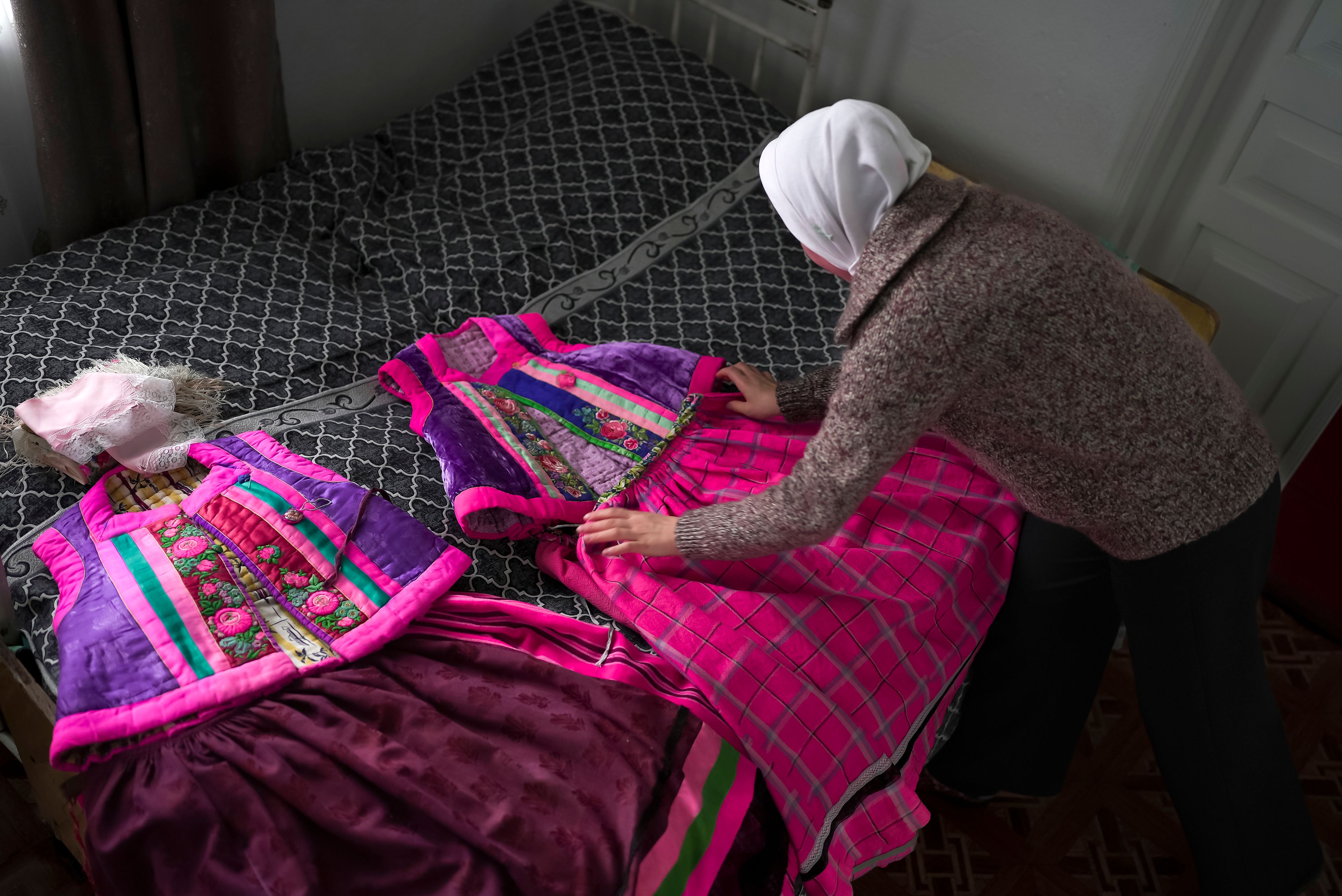 Daria Strukova lays out traditional Doukhobor dresses in her family home in the remote mountain village of Orlovka, Georgia, Sunday, May 5, 2024. (AP Photo/Kostya Manenkov)