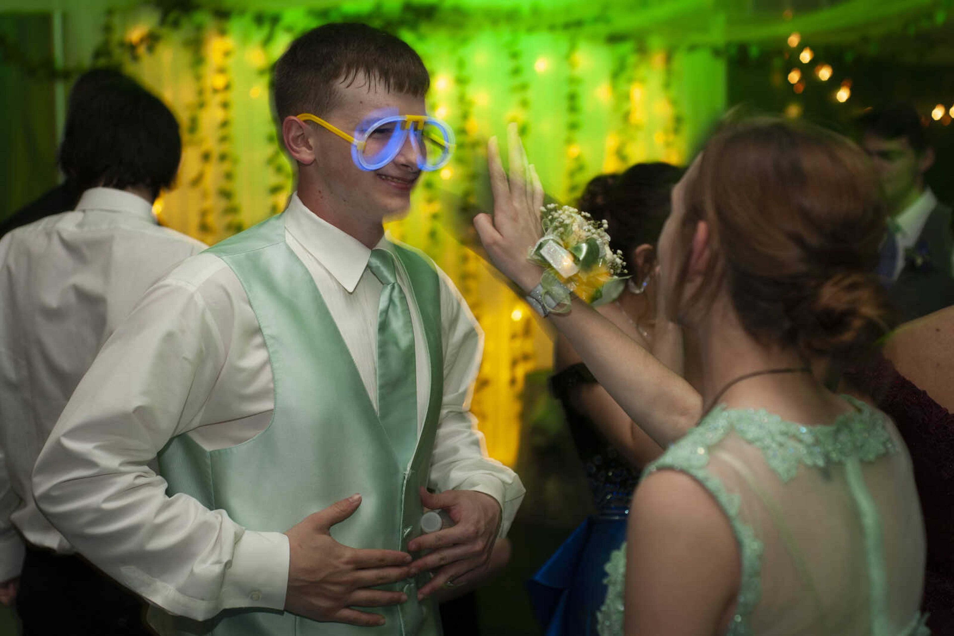 Delta junior Jon Bond wears a pair of glow-stick glasses next to Delta sophomore Harmony Cash during Delta High School's prom on Saturday, April 13, 2019, at the Delta Community Center.