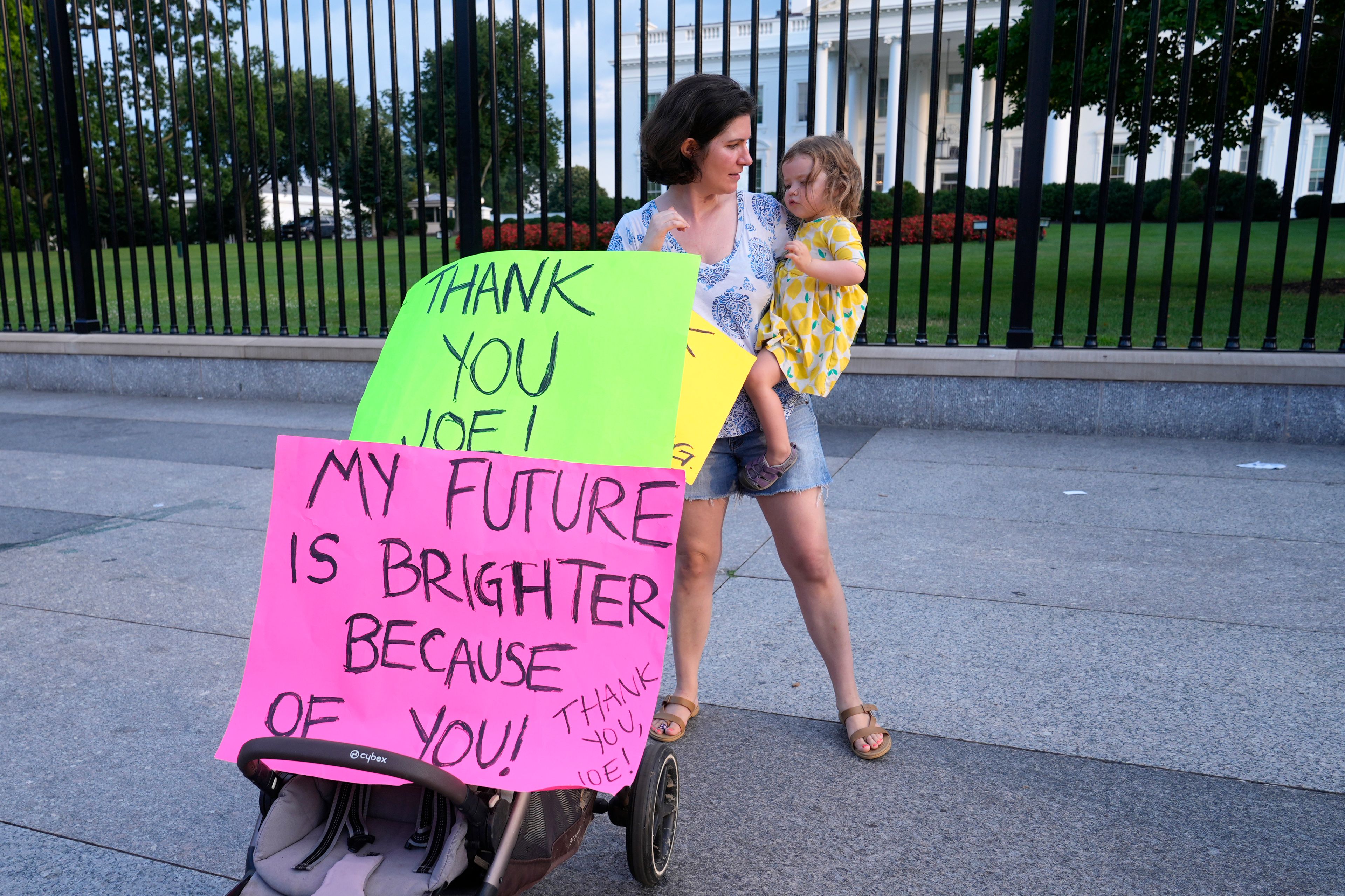 Anna Filipic, of Washington, holds her daughter Louisa Monje, 2, outside the White House in Washington, Sunday, July 21, 2024, as they show support for President Joe Biden. Biden dropped out of the 2024 race for the White House on Sunday, ending his bid for reelection following a disastrous debate with Donald Trump that raised doubts about his fitness for office just four months before the election. (AP Photo/Susan Walsh)