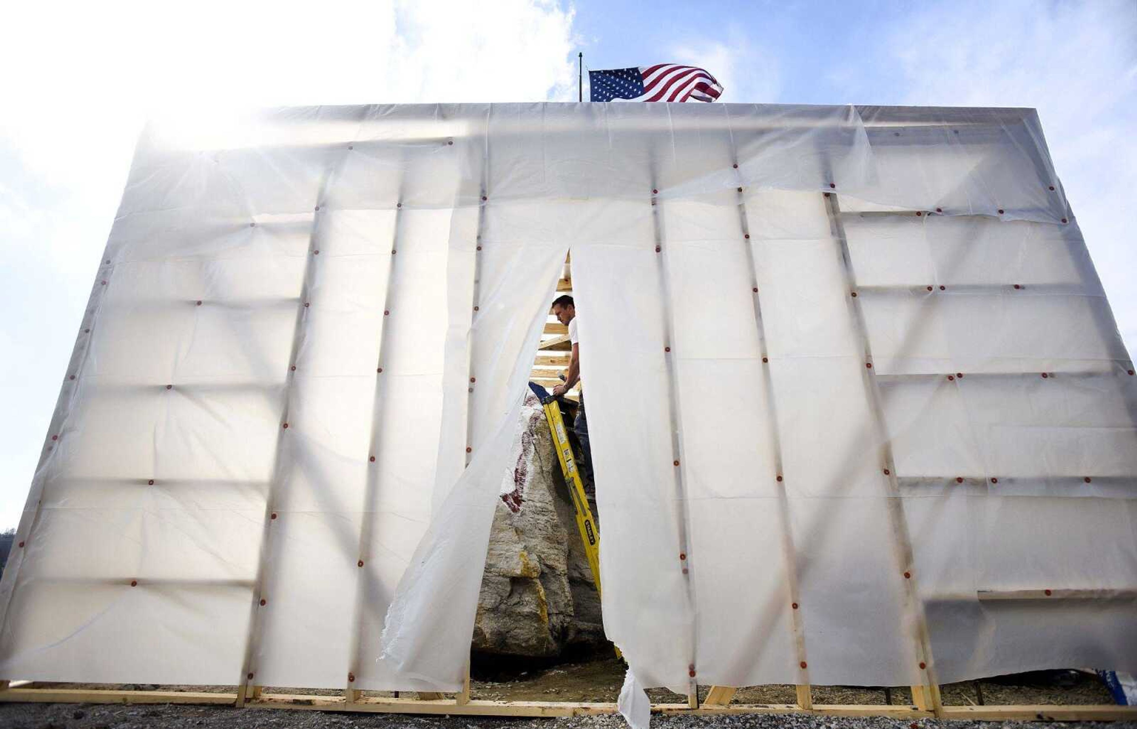 Iowa artist Ray "Bubba" Sorensen II, paints a patriotic tableau on 32-ton rock under a temporary shelter on Wednesday at Cape Girardeau County Park North. The rock is part of Veterans Plaza.