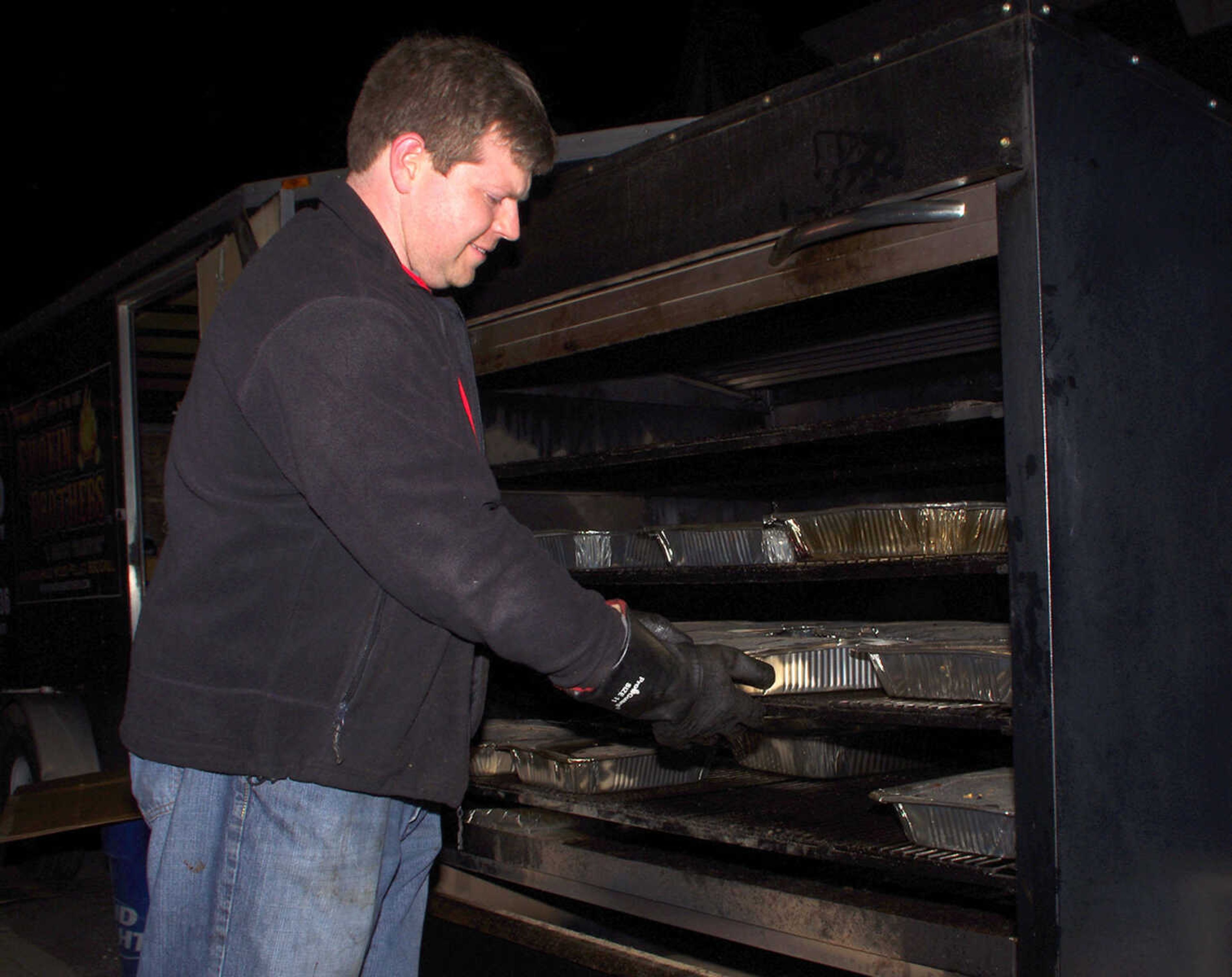 Craig Crawford with Smokin Brothers pulls out a pan of baked beans to be taken to one of the local bars participating in the 10th annual Happy Slapowitz's Toy Bash on Thursday Dec. 13, 2012.