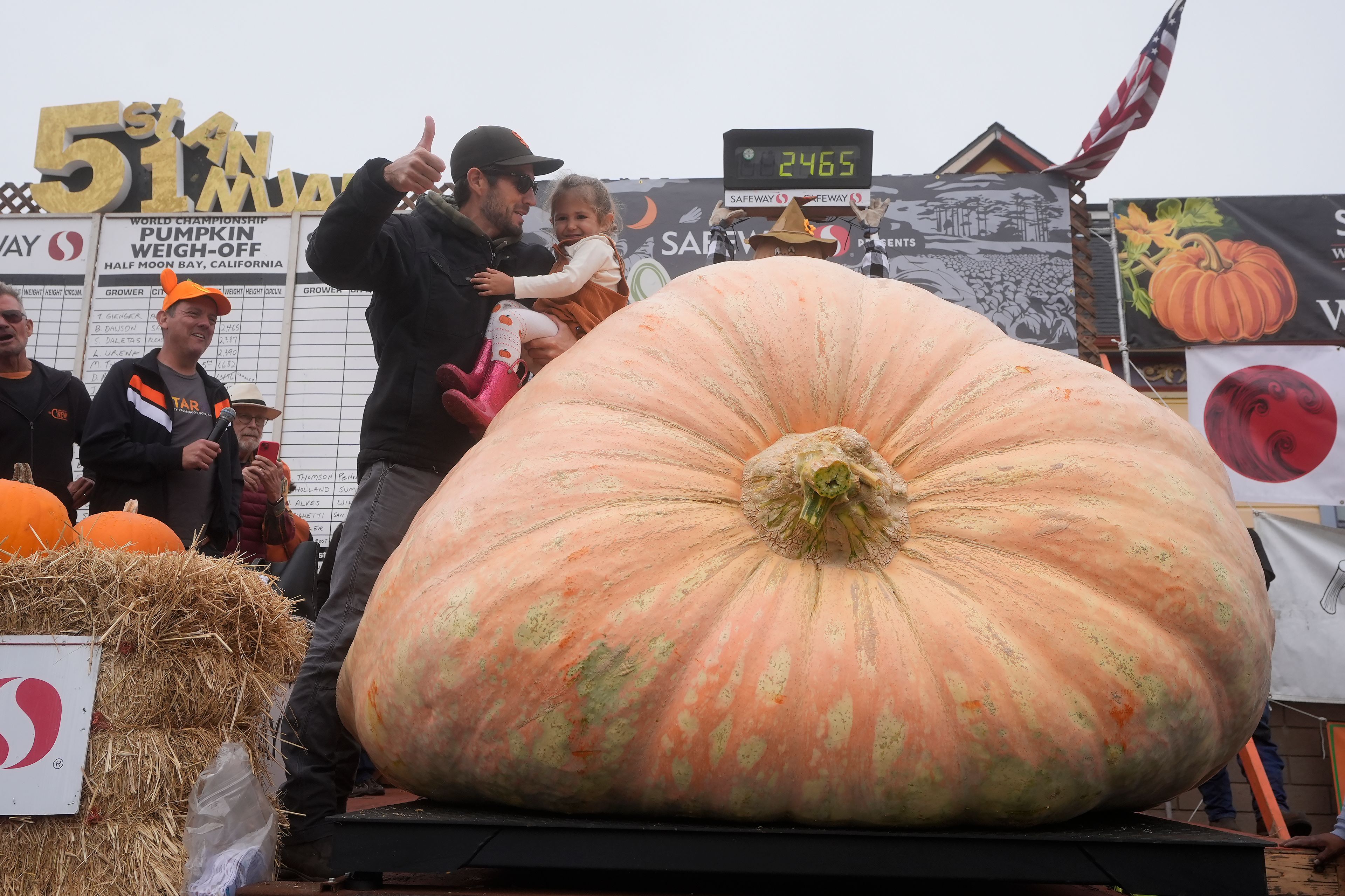 Brandon Dawson, of Sonoma County, foreground left, celebrates with his daughter Ayla, 3, after his pumpkin weighed in at 2,465 pounds at the Safeway World Championship Pumpkin Weigh-Off in Half Moon Bay, Calif., Monday, Oct. 14, 2024. (AP Photo/Jeff Chiu)