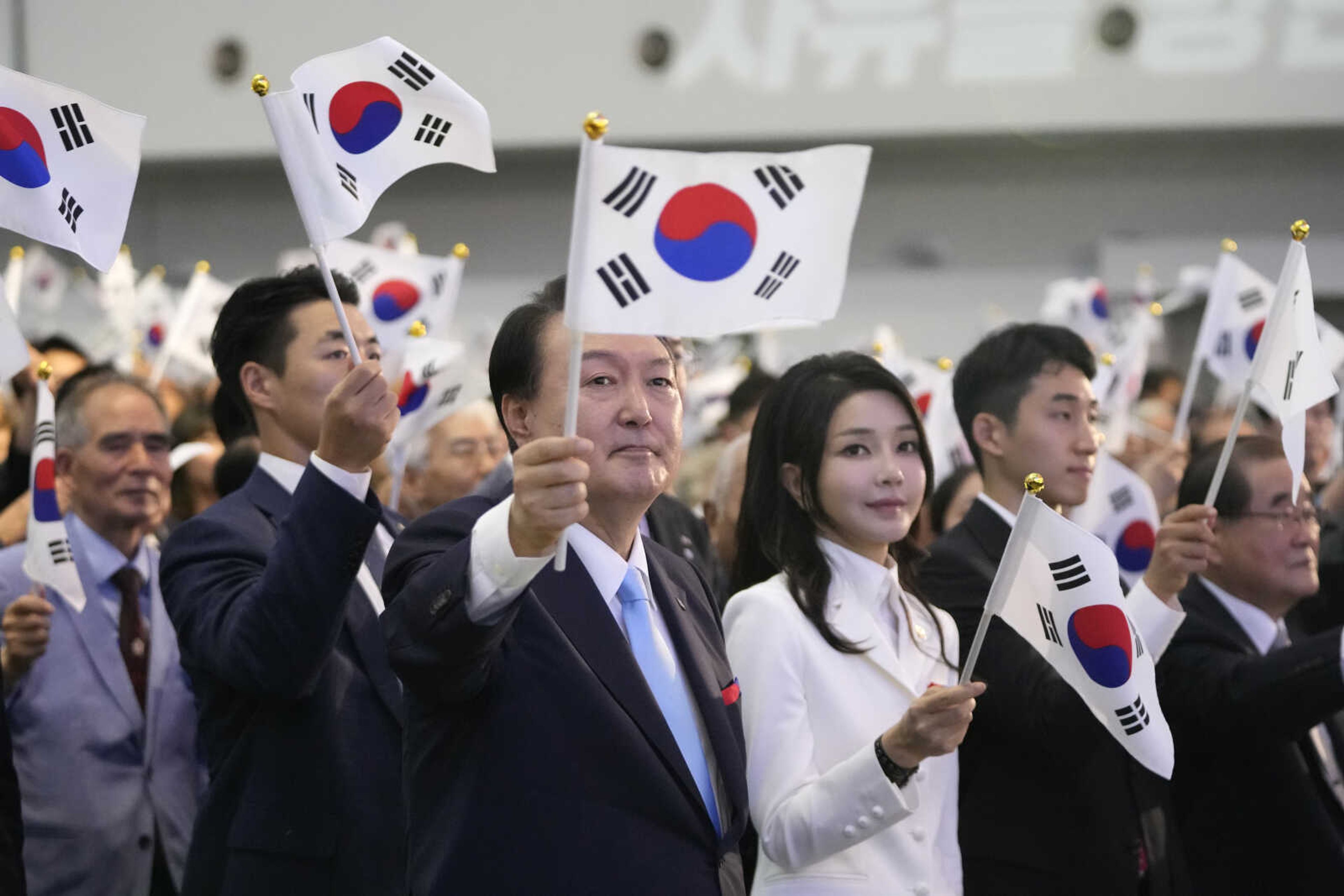 South Korean President Yoon Suk Yeol, center left, and and his wife Kim Keon Hee, center right, wave the national flags during a ceremony to celebrate the 78th anniversary of the Korean Liberation Day from Japanese colonial rule in 1945, in Seoul, South Korea, Tuesday, Aug. 15, 2023. (AP Photo/Lee Jin-man, Pool)