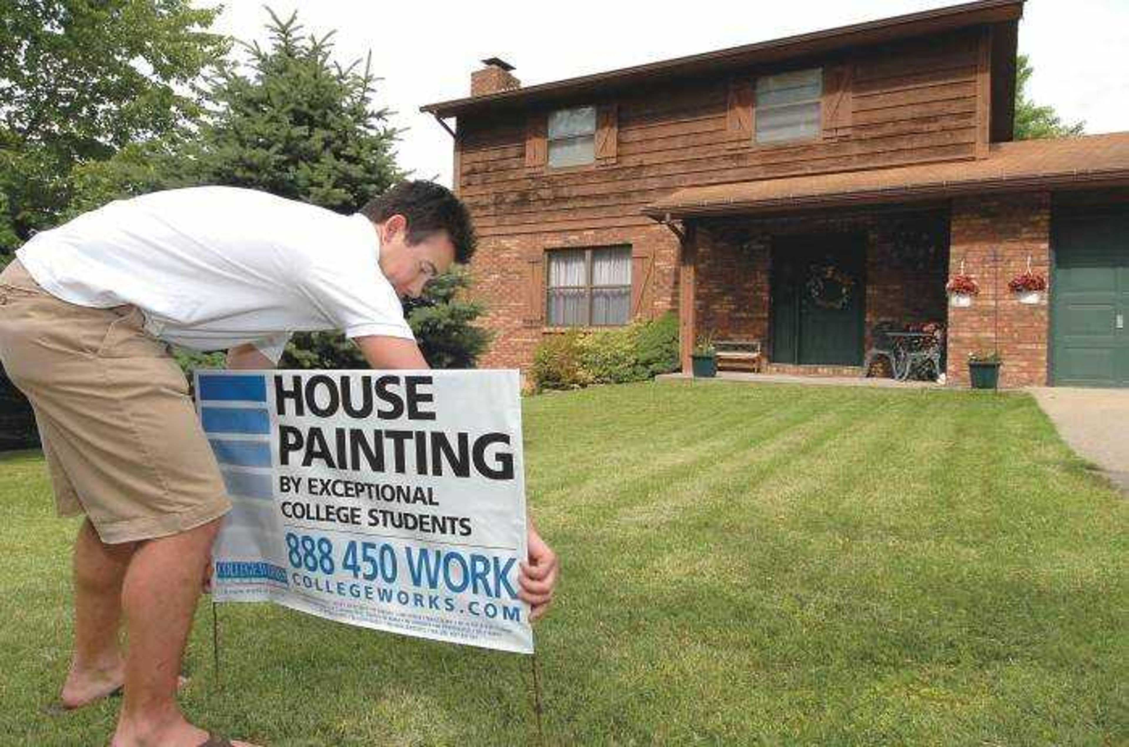 Will Browne installed one of his house-painting signs prior to estimating a painting job in Cape Girardeau on Tuesday. (Don Frazier)