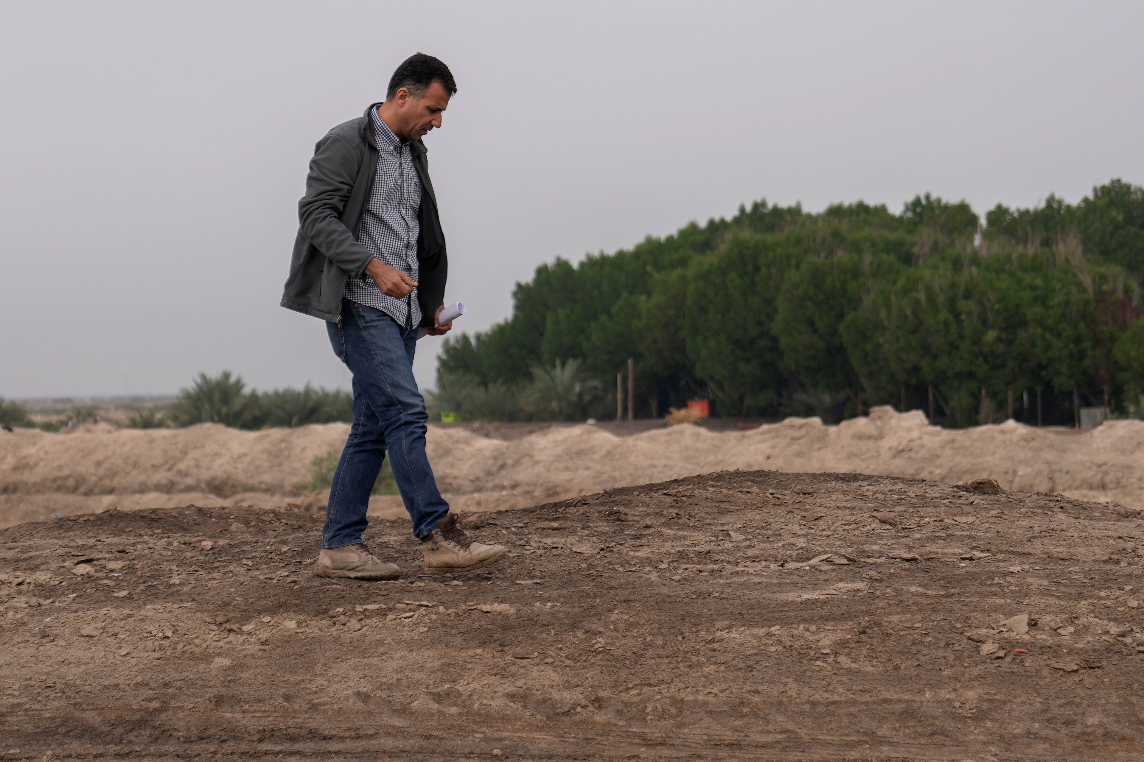 Dr Jaafar al Jotheri holds satellite images and explores the site of the Battle of al-Qadisiyah, which was fought in Mesopotamia - present-day Iraq - in the 630s AD between Arab Muslims and the army of the Sassanid Persian dynasty during a period of Muslim expansion. Abu Sakhir district- southern Najaf, Iraq, Sunday, Nov.10, 2024. (AP Photo/Hadi Mizban)