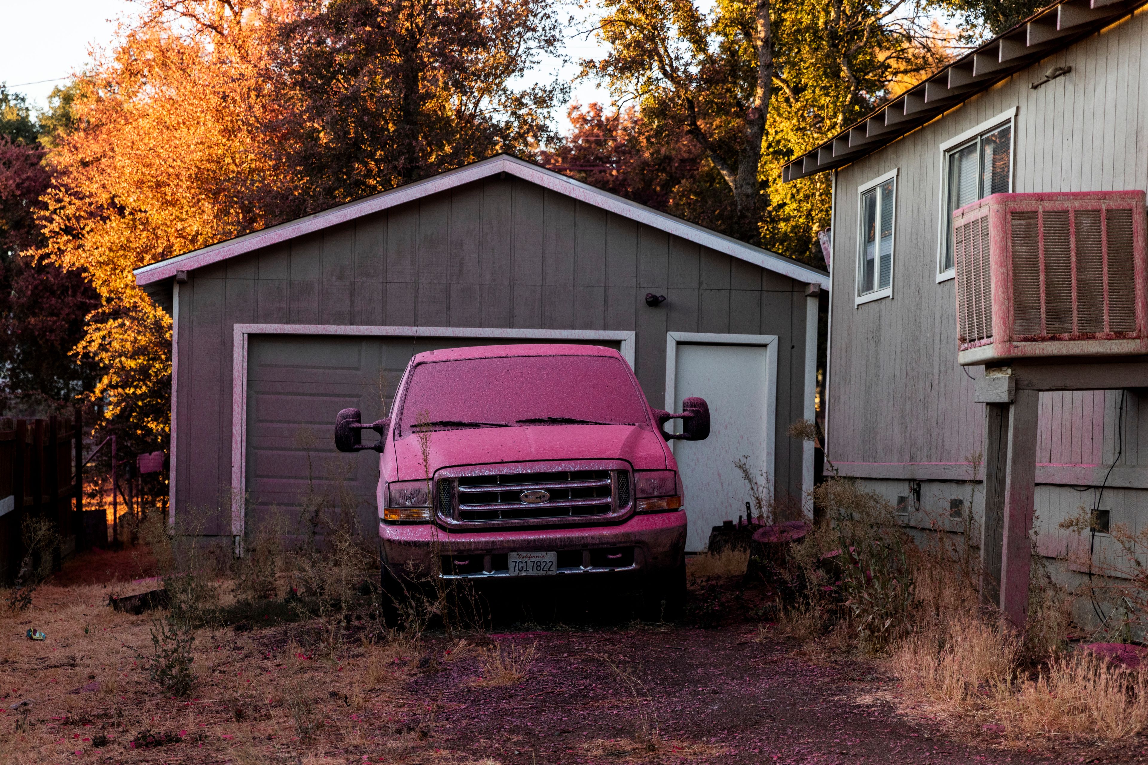 A car sits covered in fire retardant by a home during the Boyles fire in Clearlake, Calif., Sunday, Sept. 8, 2024. (Stephen Lam/San Francisco Chronicle via AP)