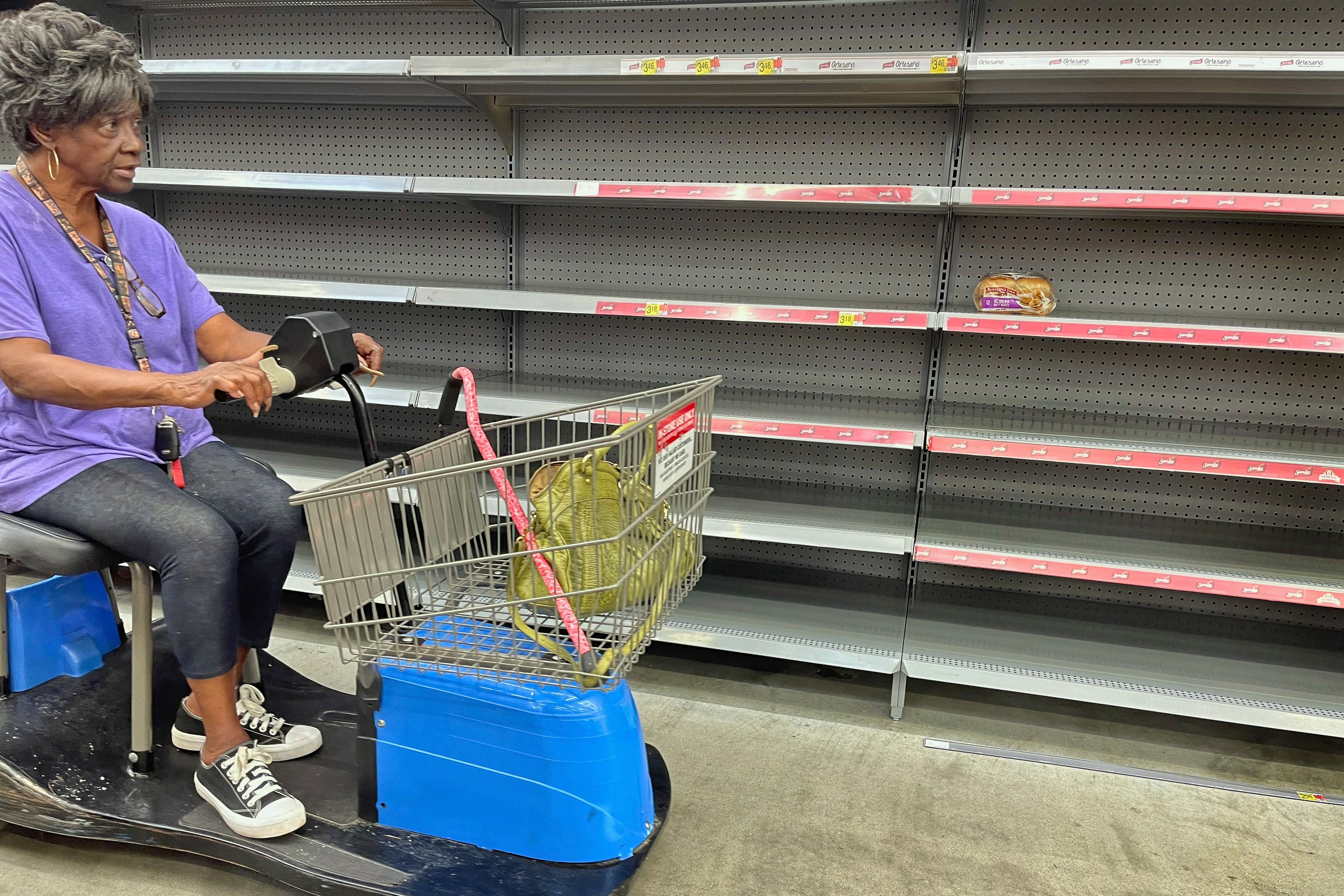 A shopper passes by empty shelves in the bread section of a Walmart, Wednesday, Sept. 25, 2024 in Tallahassee, Fla. Grocery stores and gas stations were seeing heavy traffic in advance of Hurricane Helene, expected to make landfall Thursday night in the Big Bend area. (AP Photo/Phil Sears)