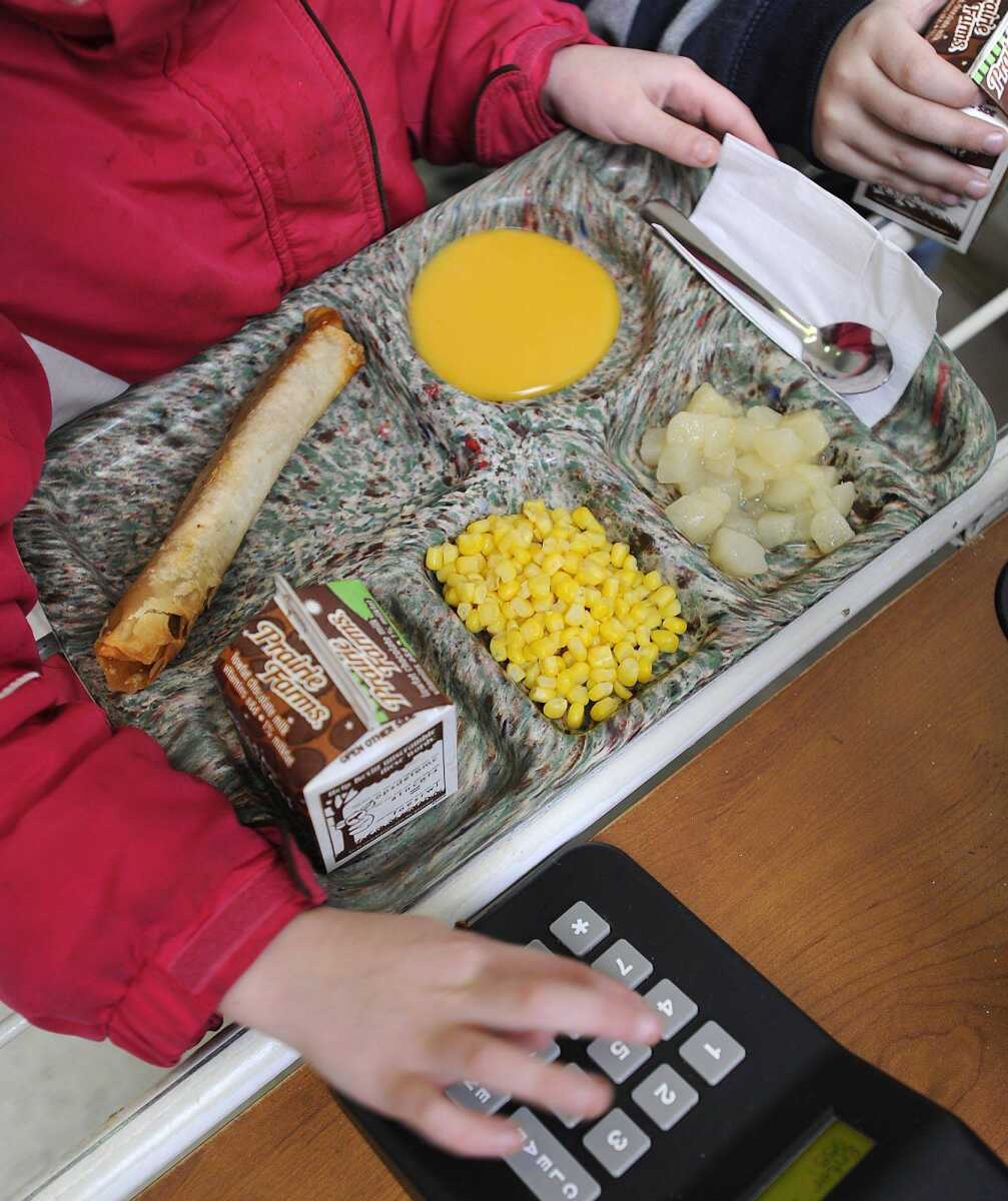 A student at Franklin Elementary School takes a lunch tray with crispito and nacho cheese sauce on the side, whole-kernel corn, chilled pears and milk. The baked crispito has a chicken chili mix inside a tortilla. (Fred Lynch)