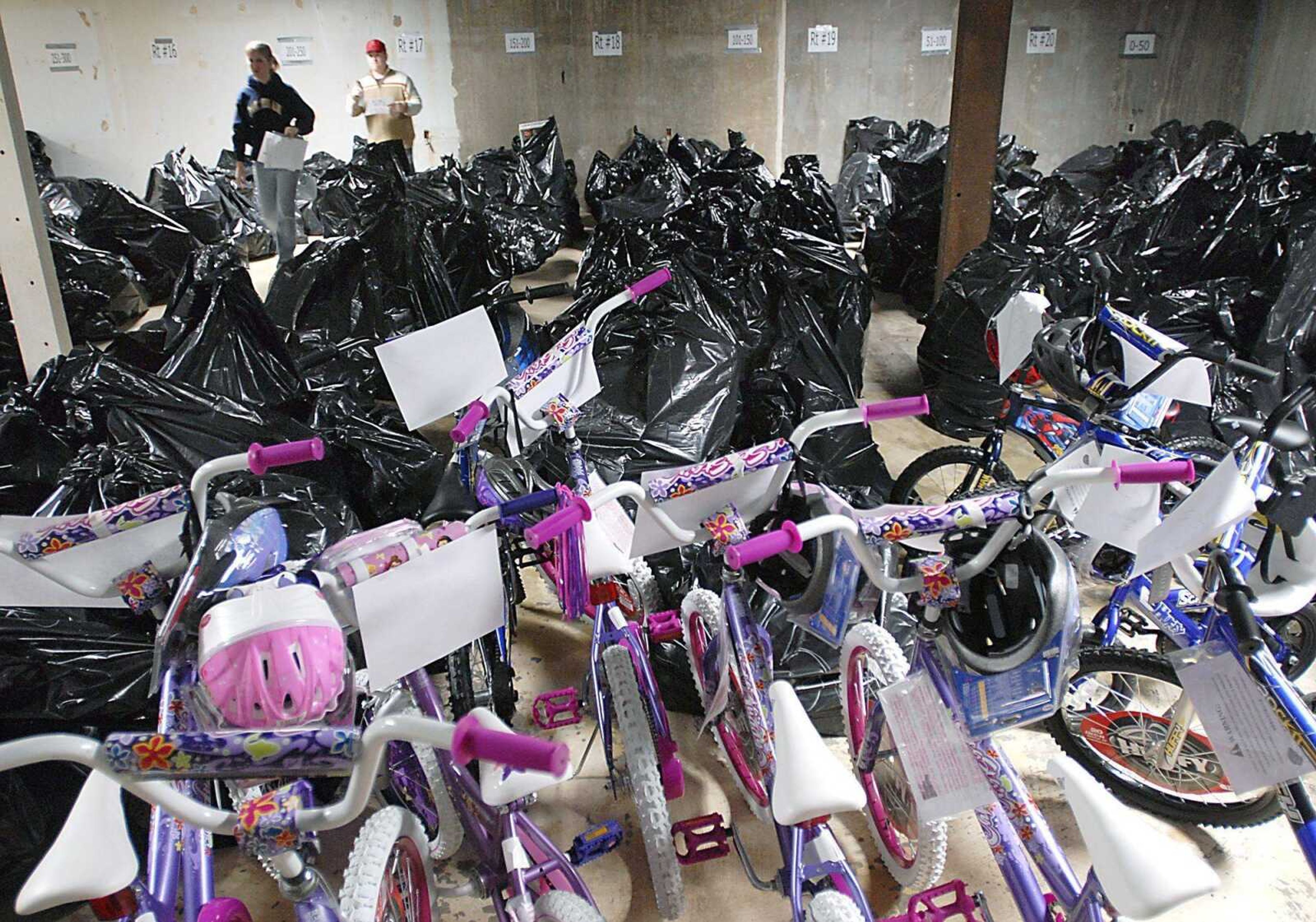 Whitney Stamp, left, and Adam Andrews organized filled gift bags for the Jaycees Toybox Tuesday night in a warehouse donated by Mark Radamaker.  More than 20 Santas will distribute the gifts Thursday. (Kit Doyle)