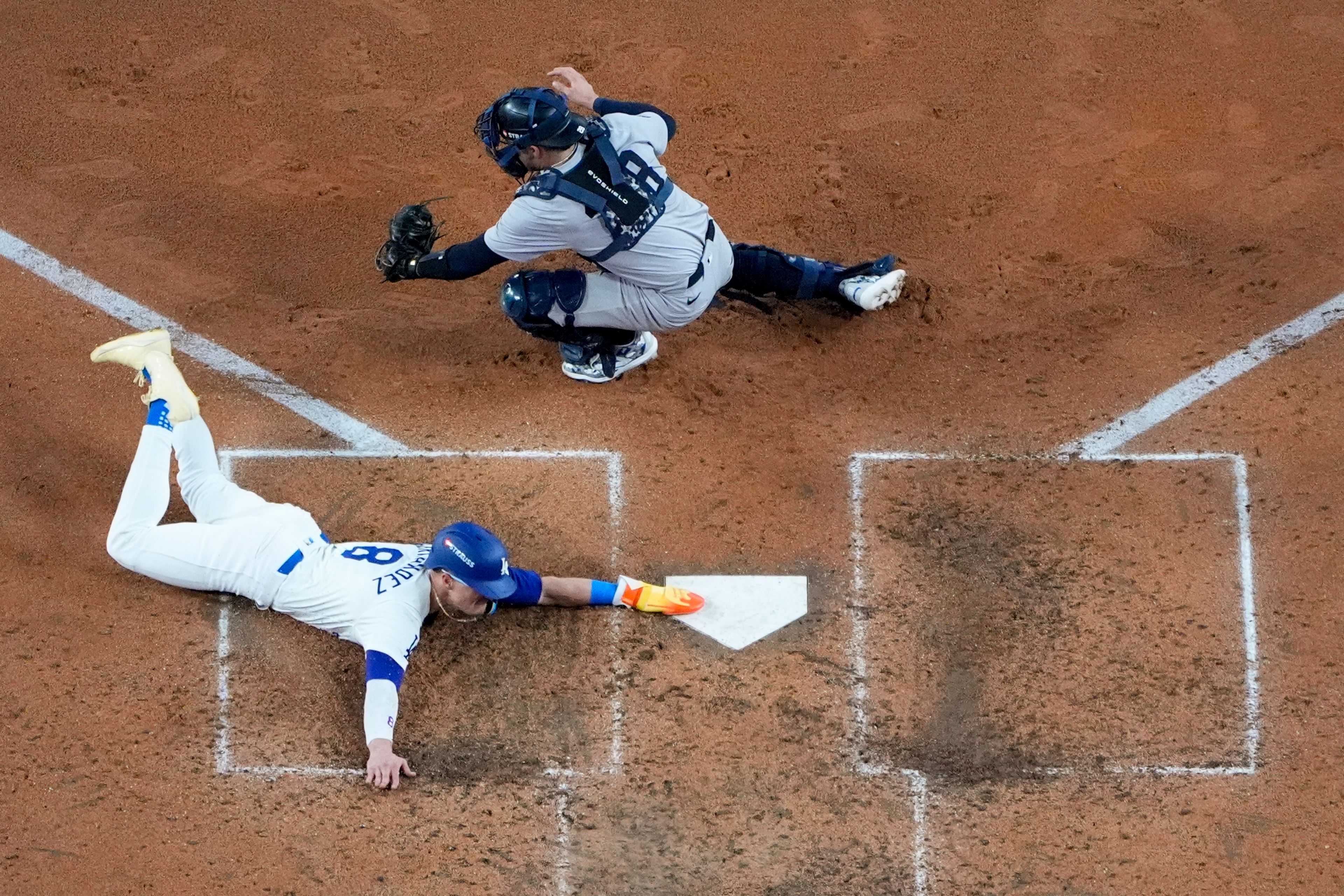 Los Angeles Dodgers' Kiké Hernández, bottom, scores past New York Yankees catcher Austin Wells on a sacrifice fly ball by Will Smith during the fifth inning in Game 1 of the baseball World Series, Friday, Oct. 25, 2024, in Los Angeles. (AP Photo/Mark J. Terrill)