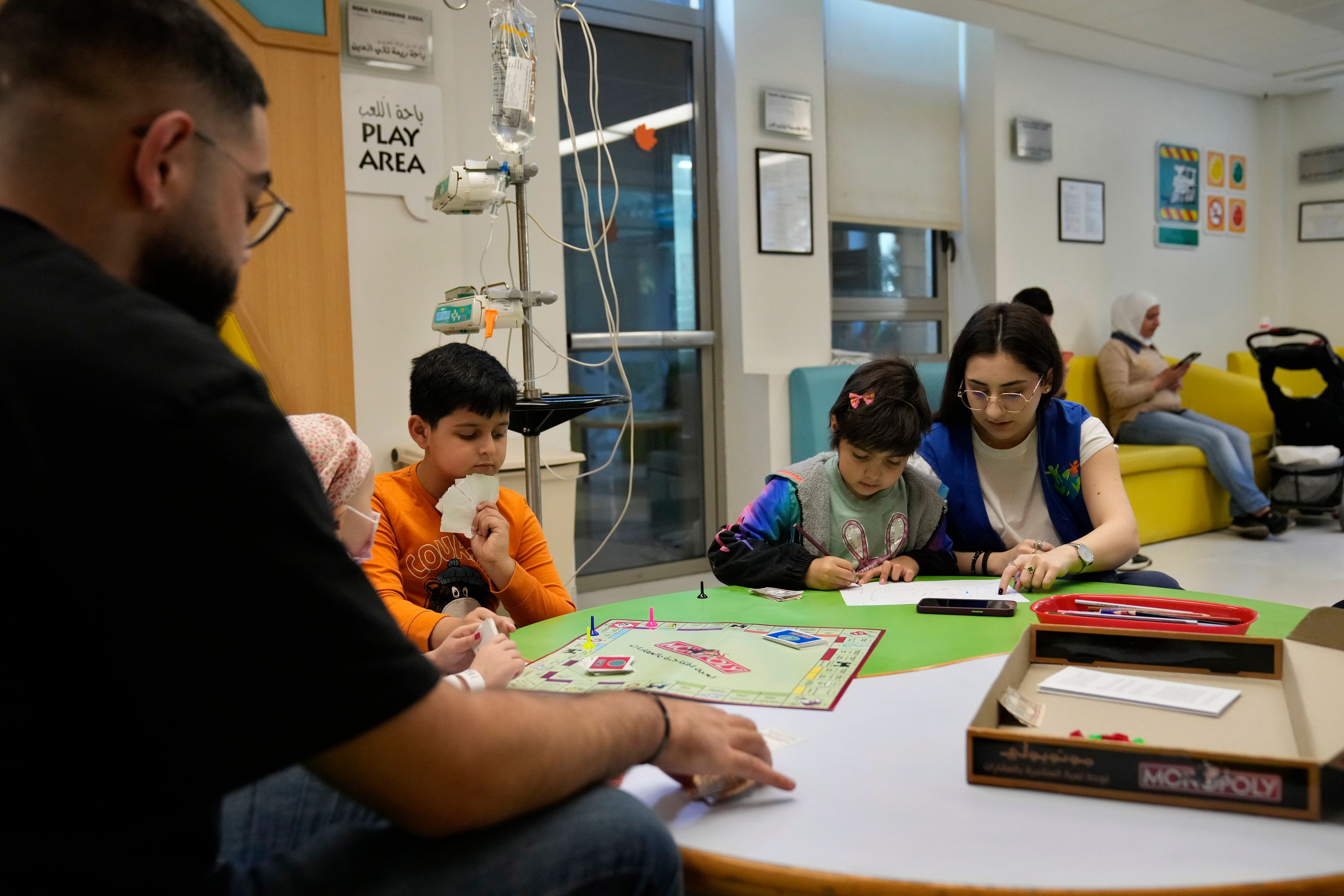 Carol Zeghayer, 9, second right, a girl who suffers from leukaemia, attends with a volunteer who offers her a compassionate care and entertainment session ahead of her treatment at the Children's Cancer Center of Lebanon, in Beirut, Lebanon, Friday, Nov. 15, 2024. (AP Photo/Hussein Malla)