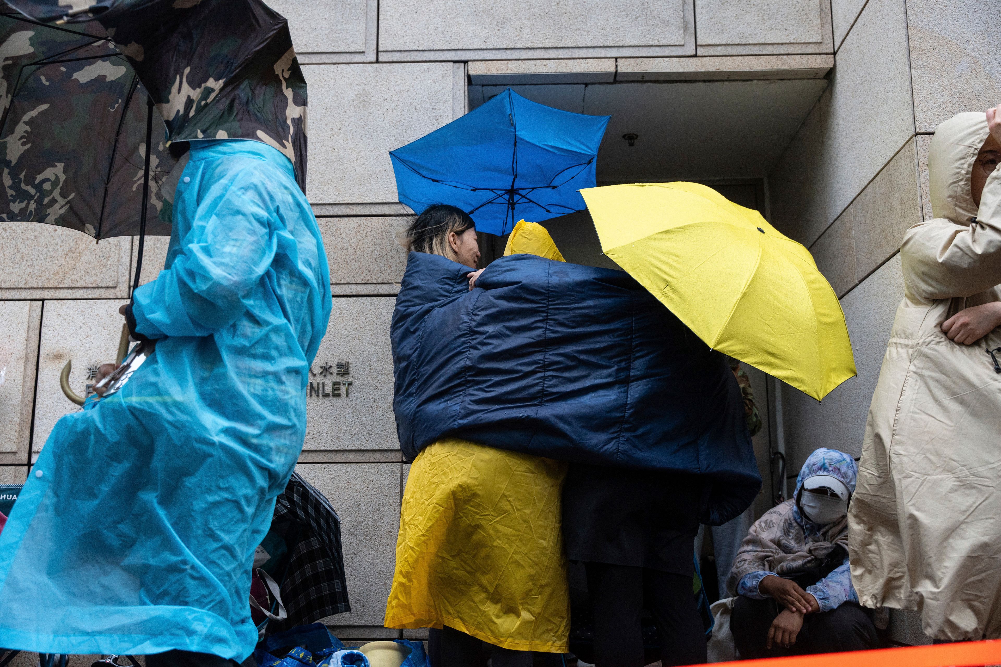 People wait outside the West Kowloon Magistrates' Courts in Hong Kong Tuesday, Nov. 19, 2024, ahead of the sentencing in national security case. (AP Photo/Chan Long Hei)