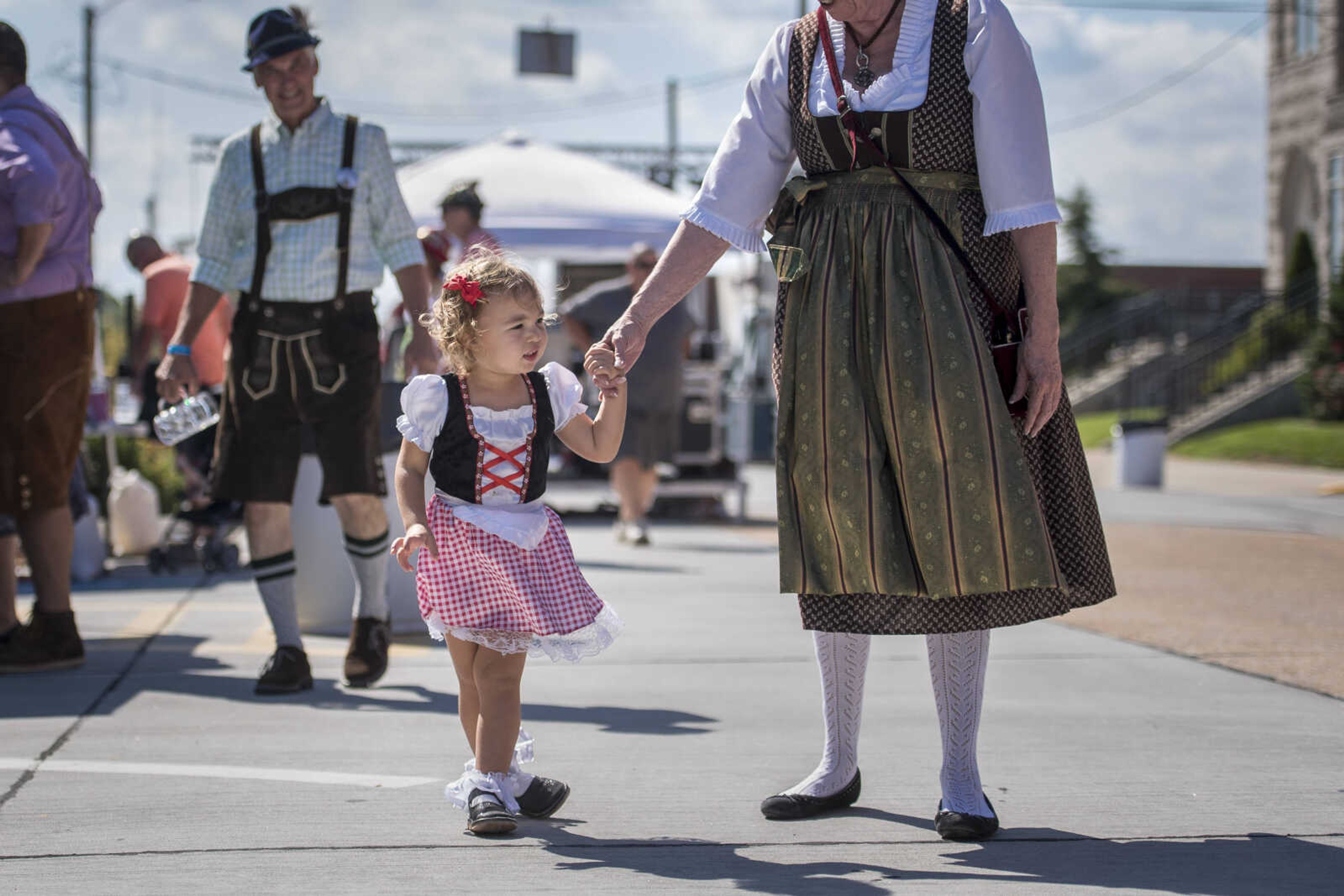 Adelaide Sanders, 2, walks in traditional German garb with her grandmother, Judy Sneathen, during Uptown Jackson Oktoberfest Saturday, Oct. 6, 2018.