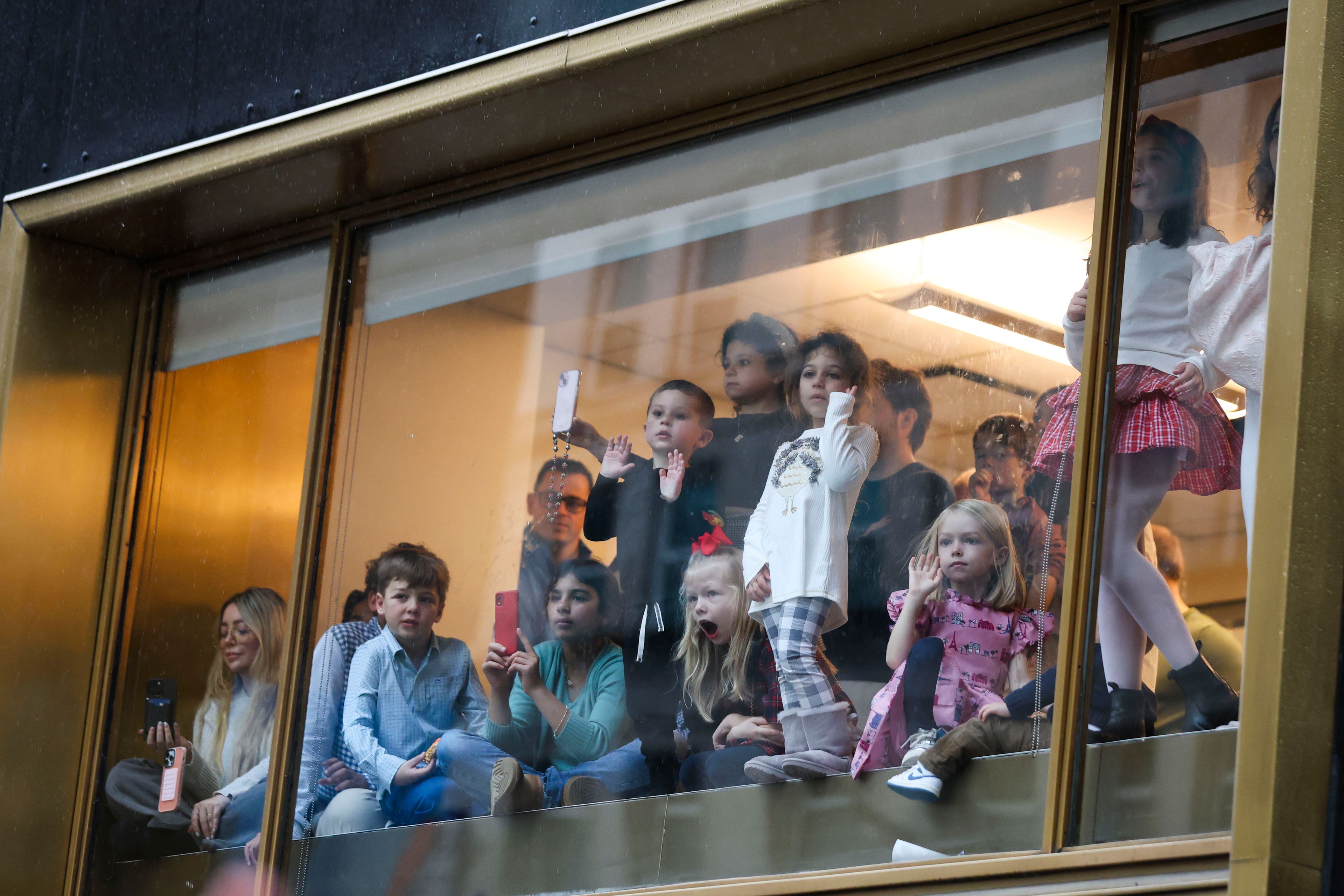 People watch from a window inside as the Macy's Thanksgiving Day Parade goes by Thursday, Nov. 28, 2024, in New York. (AP Photo/Heather Khalifa)