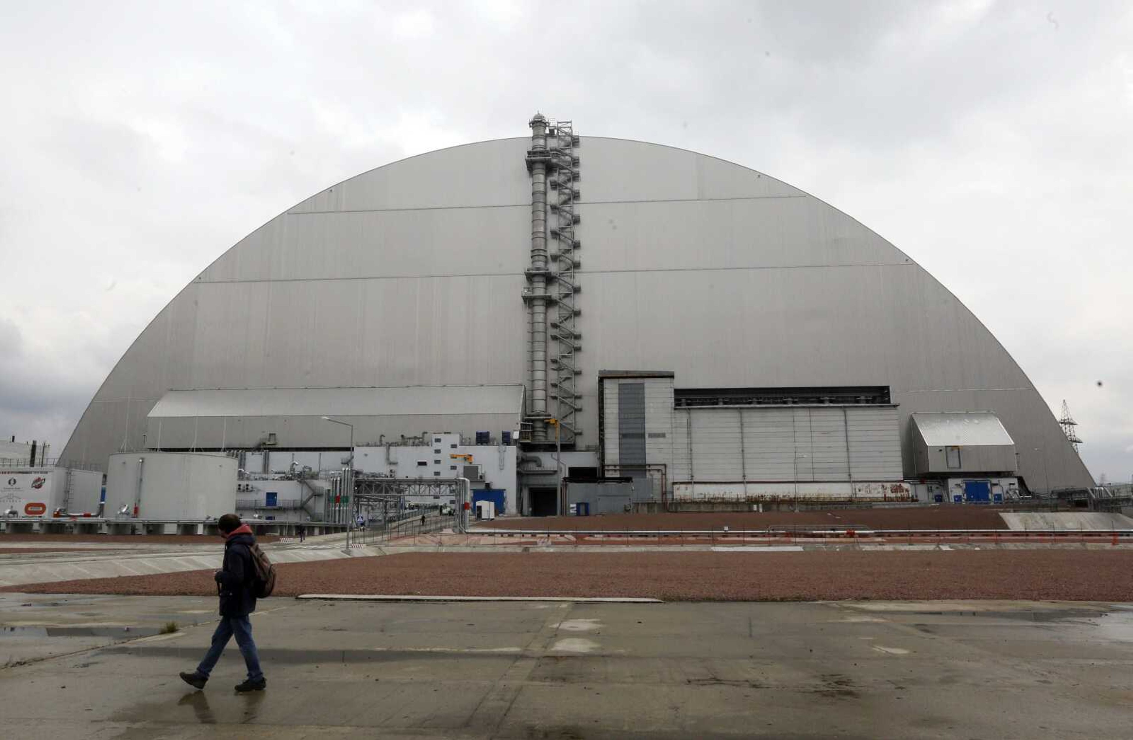 A man walks past a shelter covering the exploded reactor at the Chernobyl nuclear plant April 15 in Chernobyl, Ukraine.