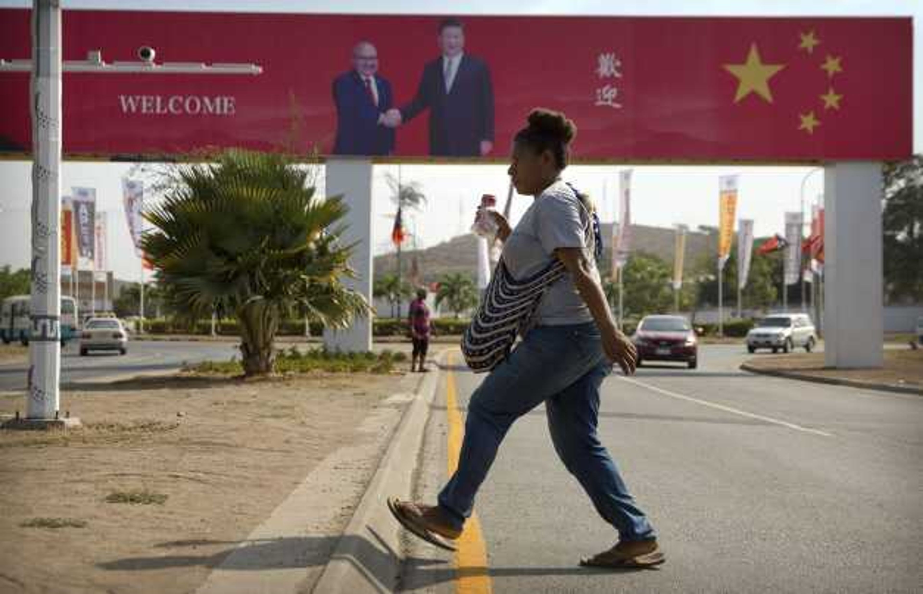 A woman crosses the street near a billboard commemorating the state visit of Chinese President Xi Jinping on Nov. 15, 2018, in Port Moresby, Papua New Guinea.