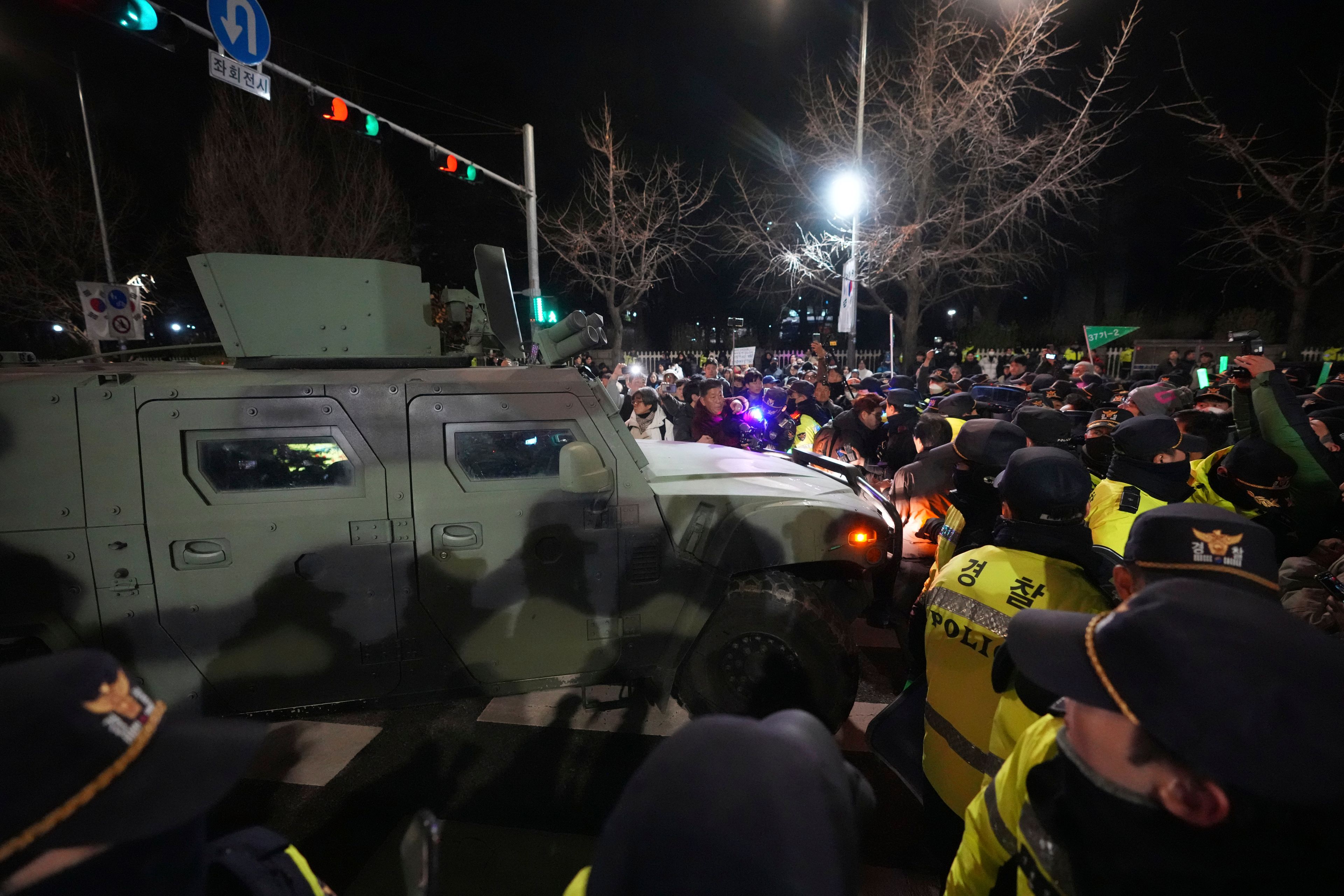 Military vehicle is escorted by police officers as people try to block outside of the National Assembly in Seoul, South Korea, Wednesday, Dec. 4, 2024. (AP Photo/Lee Jin-man)