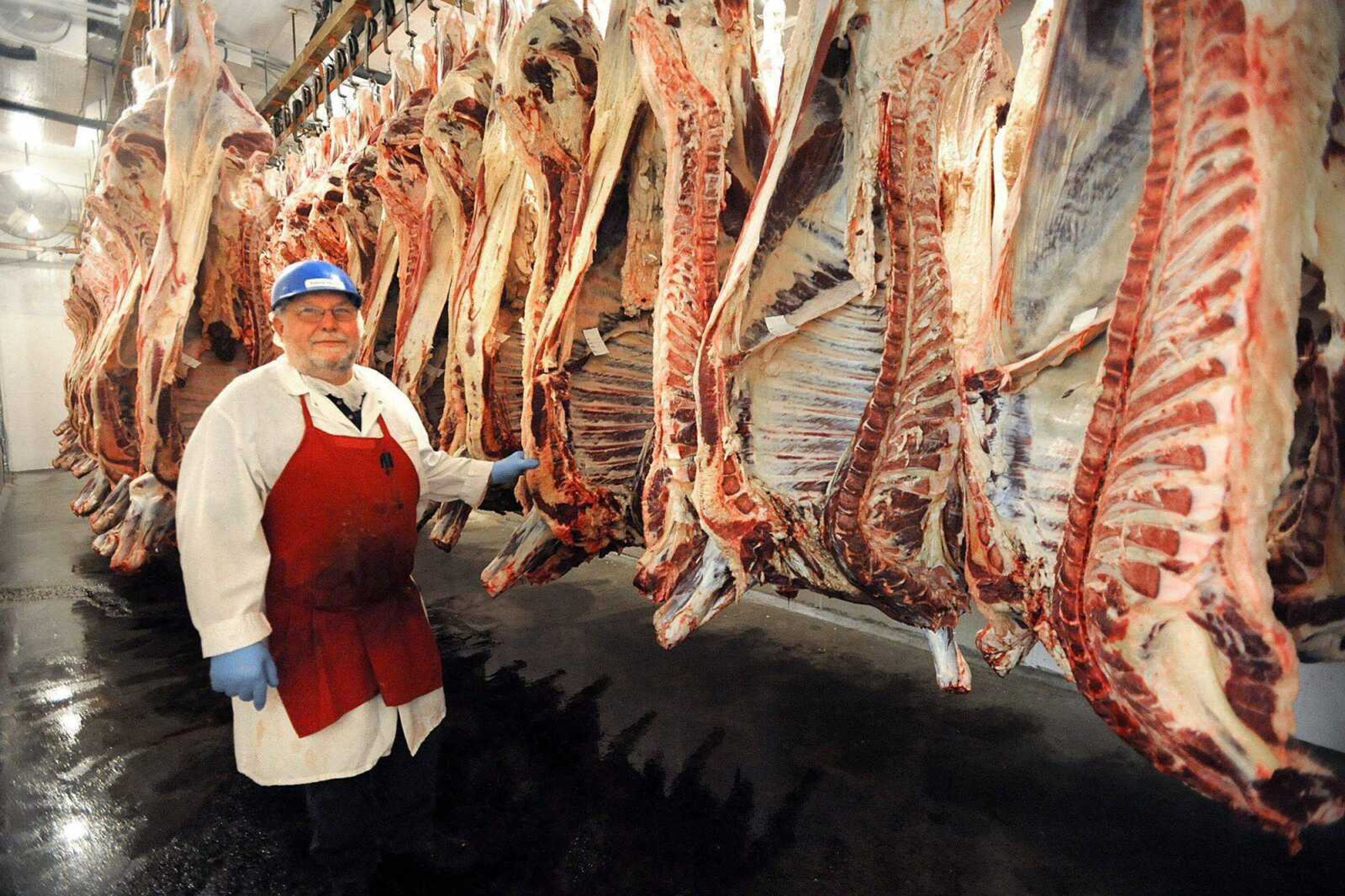 Butcher Kenny Klipfel stands in the meat cooler in 2012 with cow halves waiting to be butchered Thursday at Fruitland American Meats.