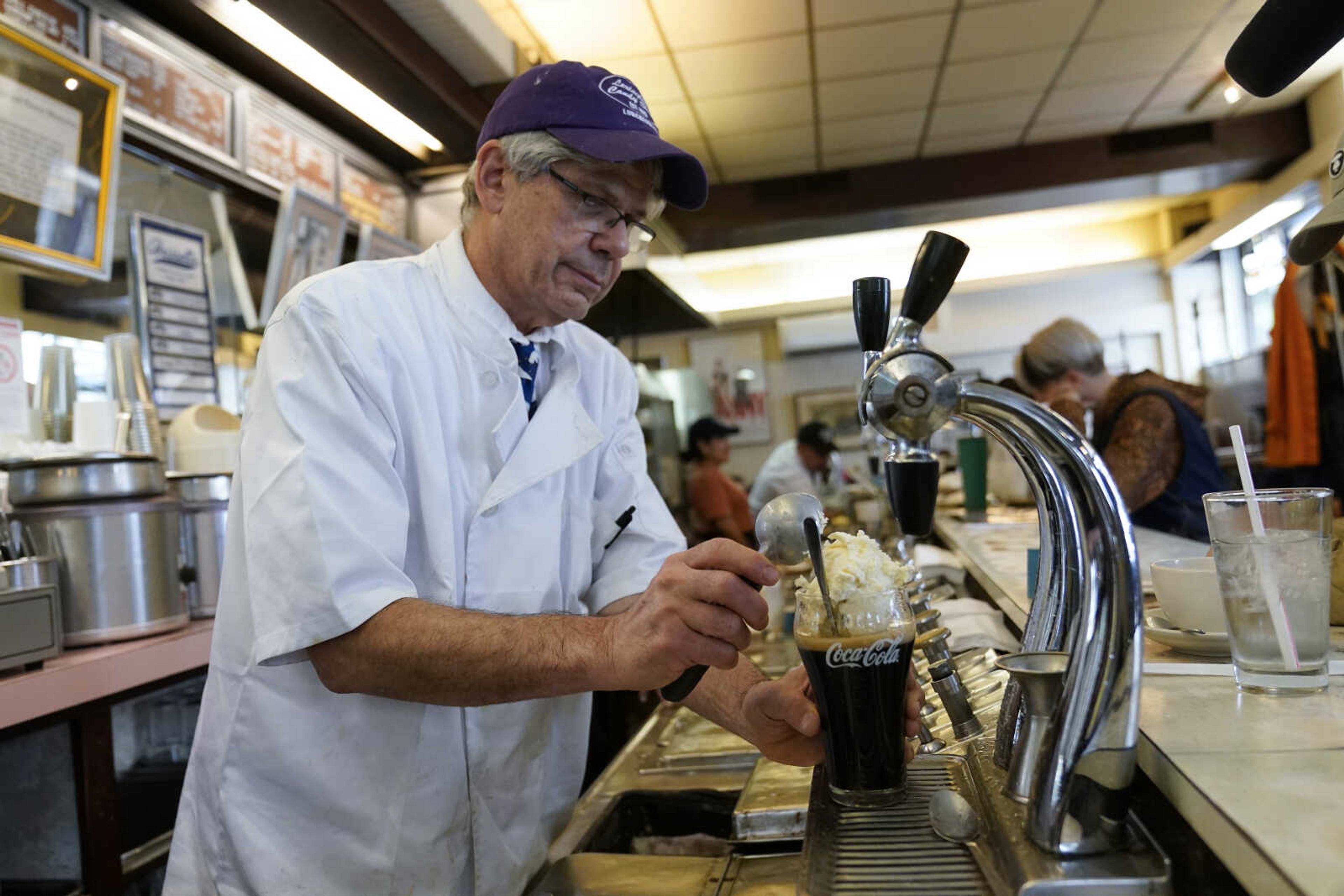 John Philis, a third-generation owner of the Lexington Candy Shop, prepares a Coke float at the luncheonette Sept. 28 in New York.