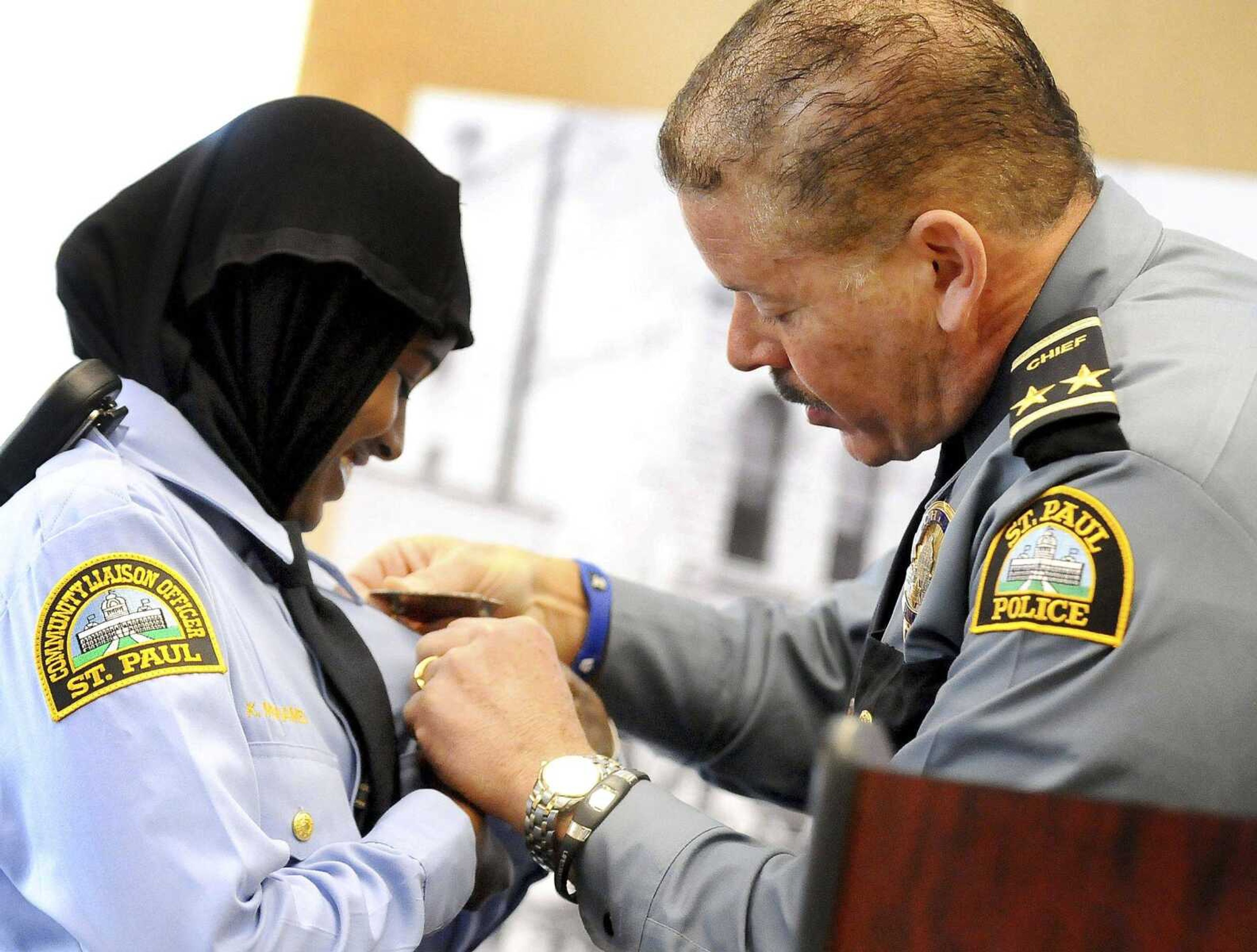 Community officer Kadra Mohamed, left, smiles as she receives her badge March 1, 2014, from St. Paul, Minnesota, police chief Thomas Smith, during a ceremony for  East African Junior Police Academy in St. Paul.