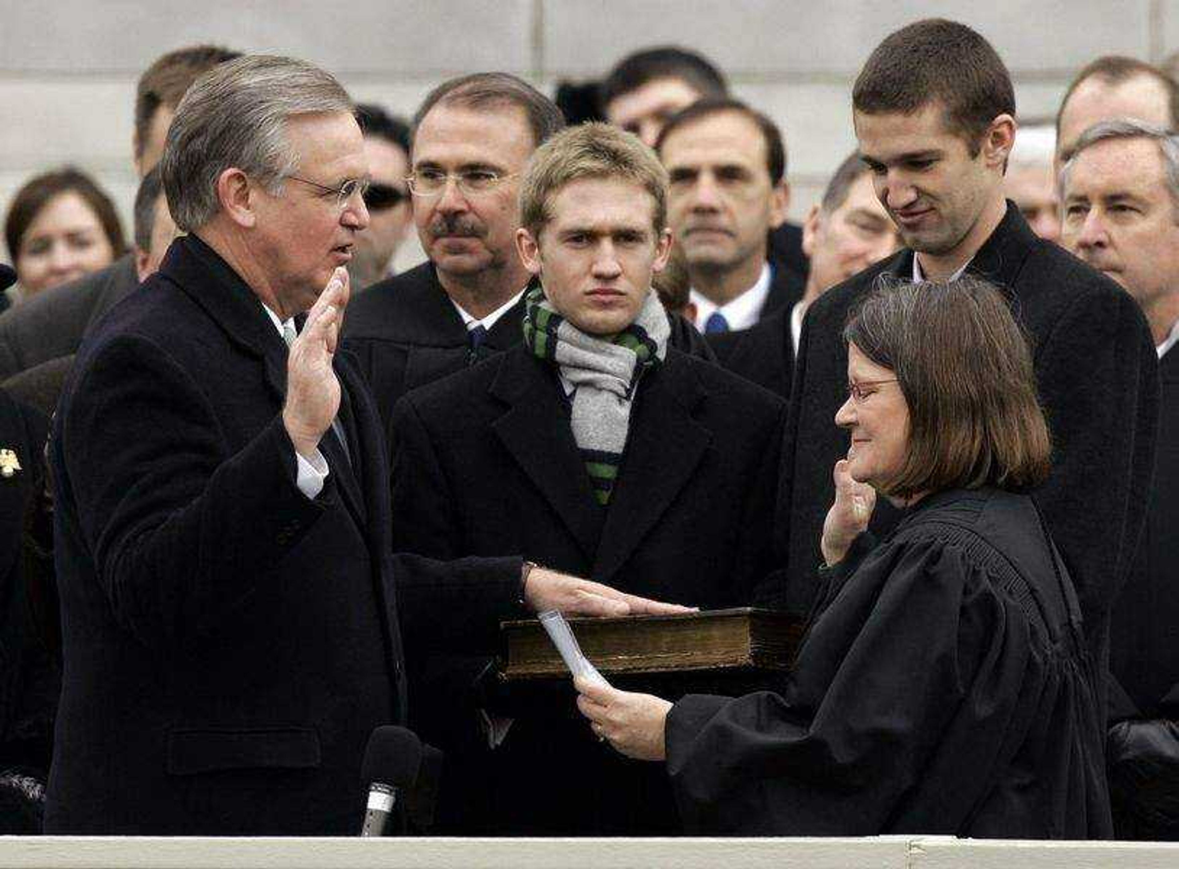 Missouri Gov.-elect Jay Nixon, left, is sworn in as Missouri's 55th governor by Missouri Supreme Court Chief Justice Laura Denvir Stith, right, as Nixon's sons Jeremiah, center and Will, back right, look on Monday, Jan. 12, 2008, in Jefferson City, Mo. Nixon, who served 16 years as attorney general, easily won the Nov. 4 gubernatorial election over Republican Rep. Kenny Hulshof and is succeeding Republican Gov. Matt Blunt, who chose not to seek re-election. (AP Photo/Jeff Roberson)