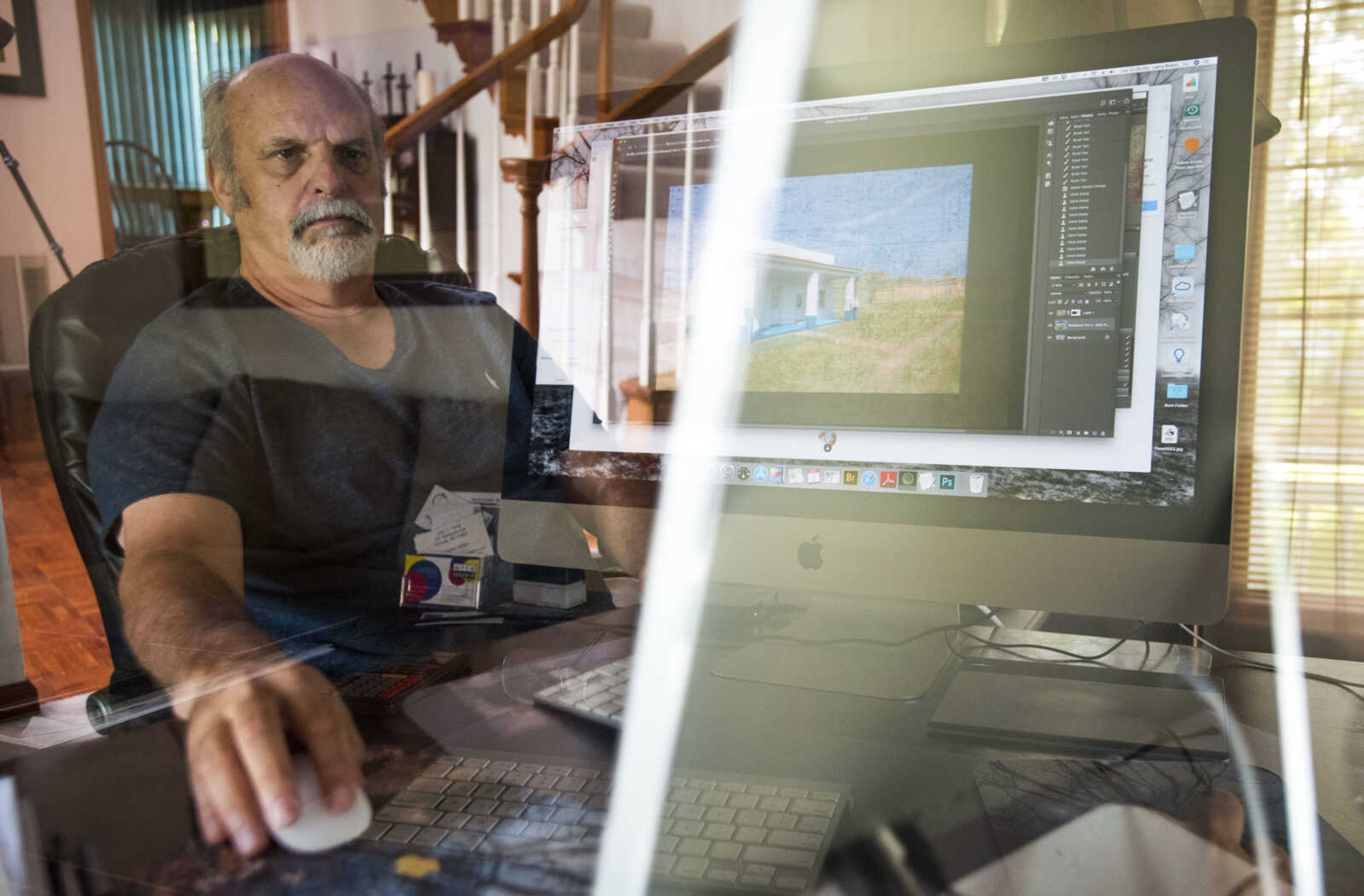 In this in-camera double exposure photograph, photographer Larry Braun is seen editing a photo of a Holcomb, Missouri, library at his home in Benton, Missouri.