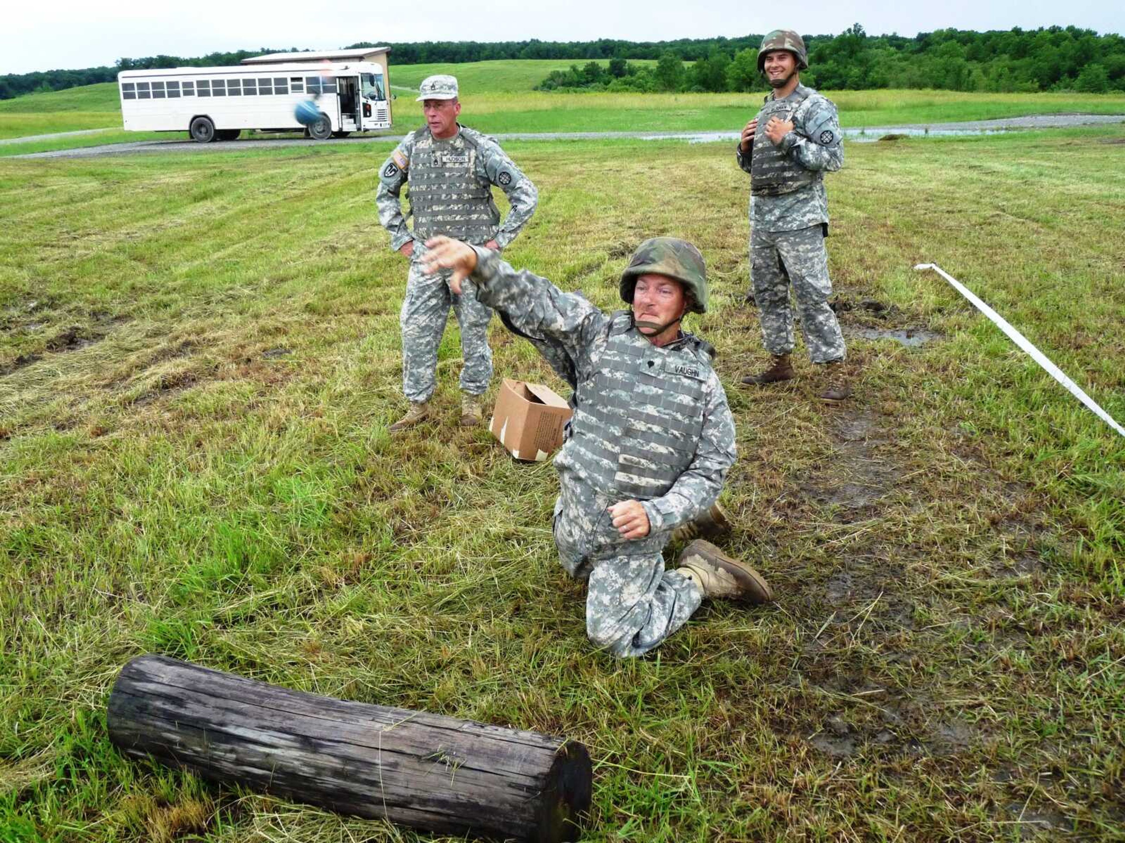 Spc. David Vaughn throws a grenade simulator at a target while training NCO Staff Sgt. David Hudson and Spc. Dillon Rickman observe.