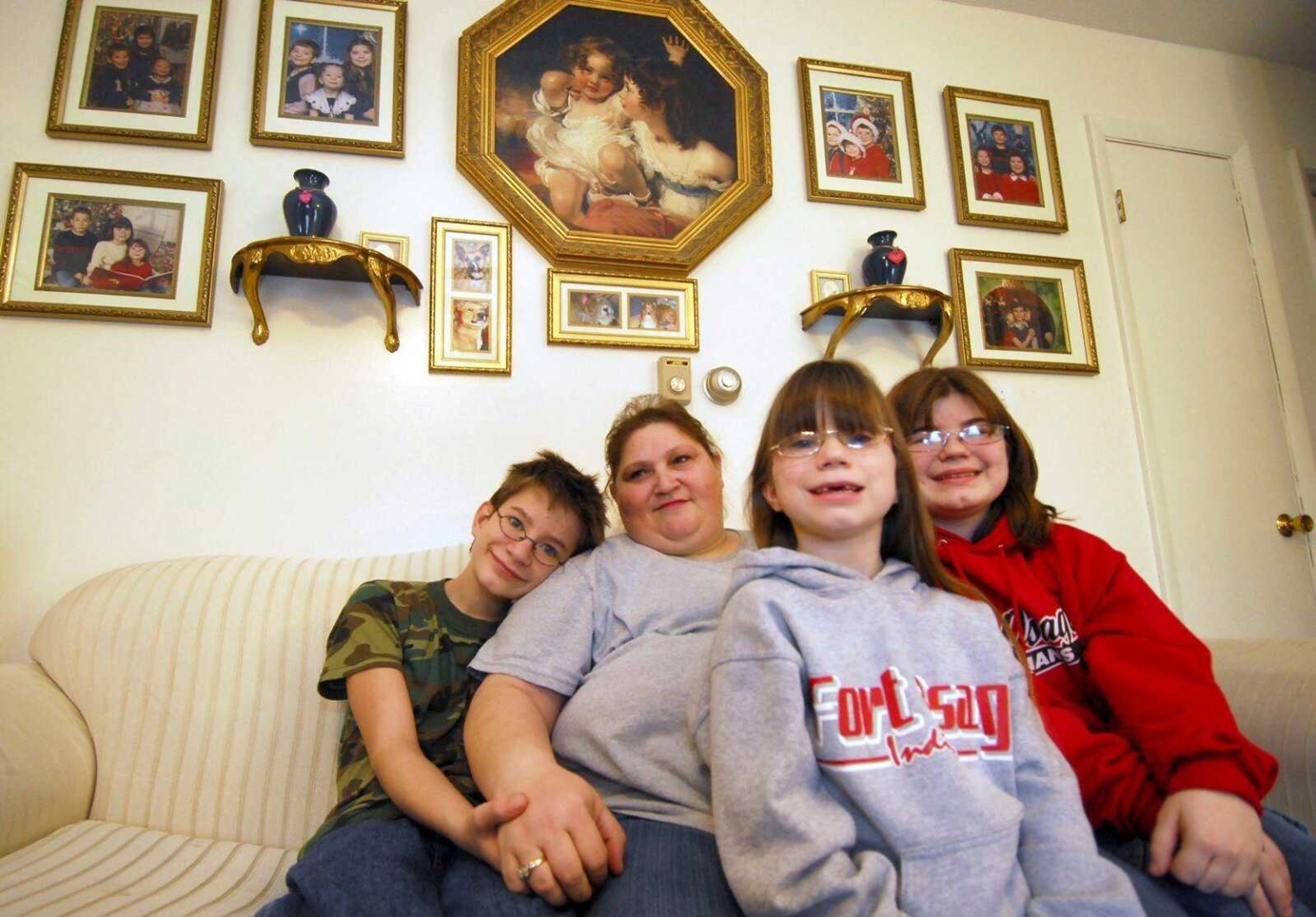 Surrounded by family Christmas pictures, Helen Martin, center, sat with her three children, Michael, 13, left, Ann, 8, and Sara, 16, on Dec. 21 in her living room in Independence, Mo. First a foster mother to the three children, Helen permanently adopted them into the family last September after a four-year battle in court. (Amy Elrod ~ The Examiner)