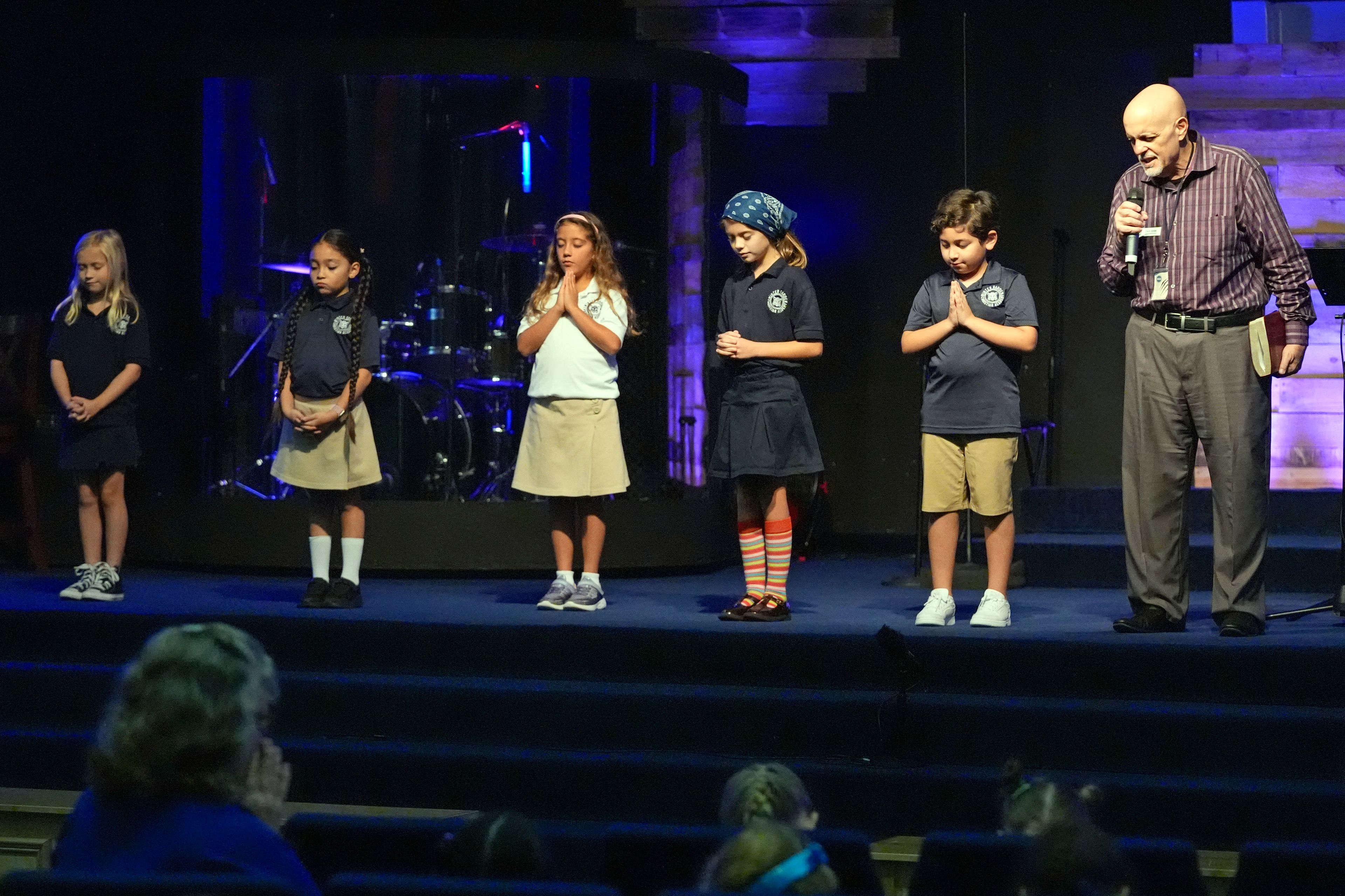 Academy Administrator Clark Rivas, far right, leads students in a prayer during a chapel service at the Winter Garden Christian Academy Thursday, Aug. 29, 2024, in Winter Garden, Fla. (AP Photo/John Raoux)