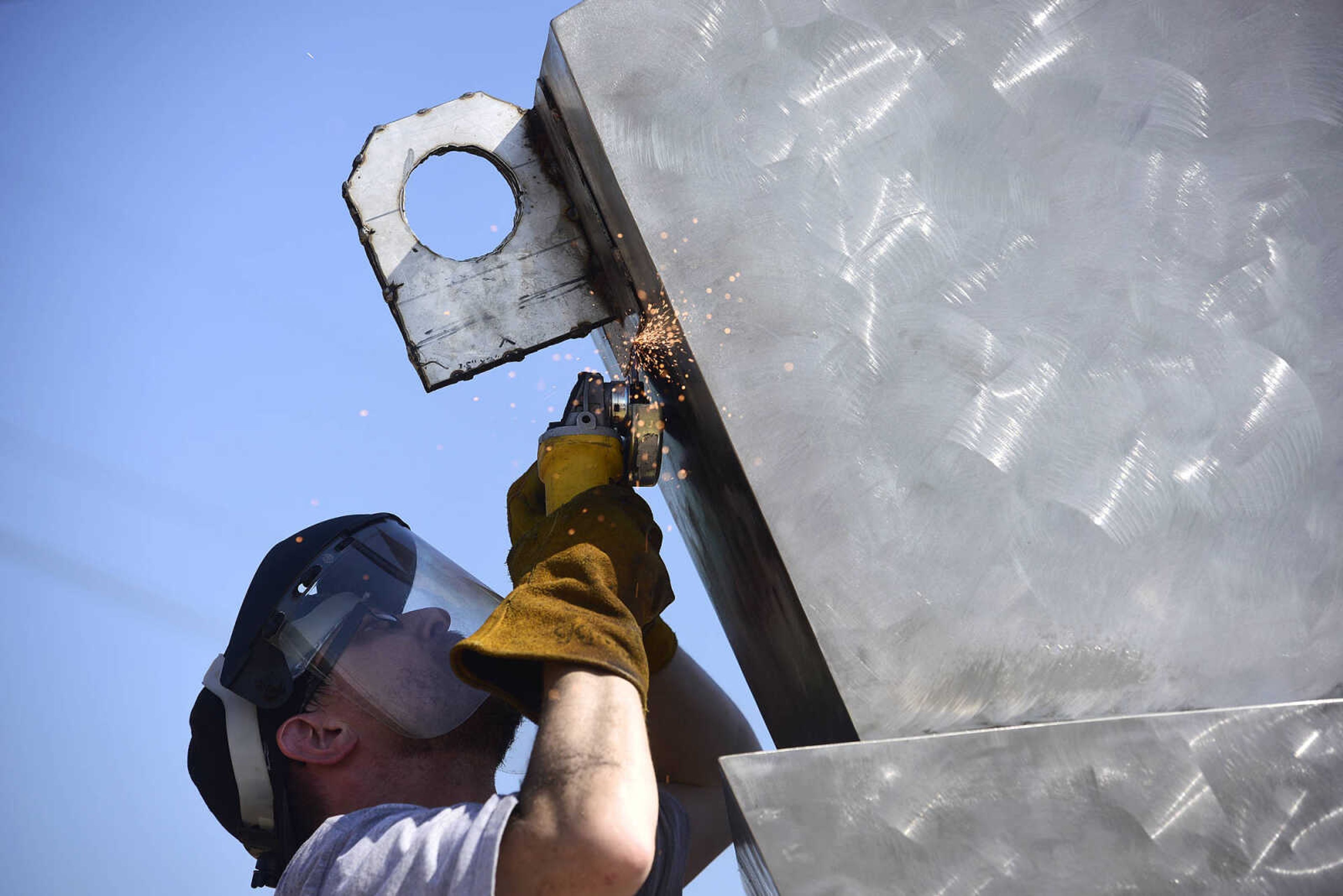 Chris Wubbena cuts an eyelet off of his sculpture, "Commence" that was used to help install the two-piece 14-foot sculpture in the Fountain Street roundabout on Monday, July 24, 2017, near the River Campus in Cape Girardeau.