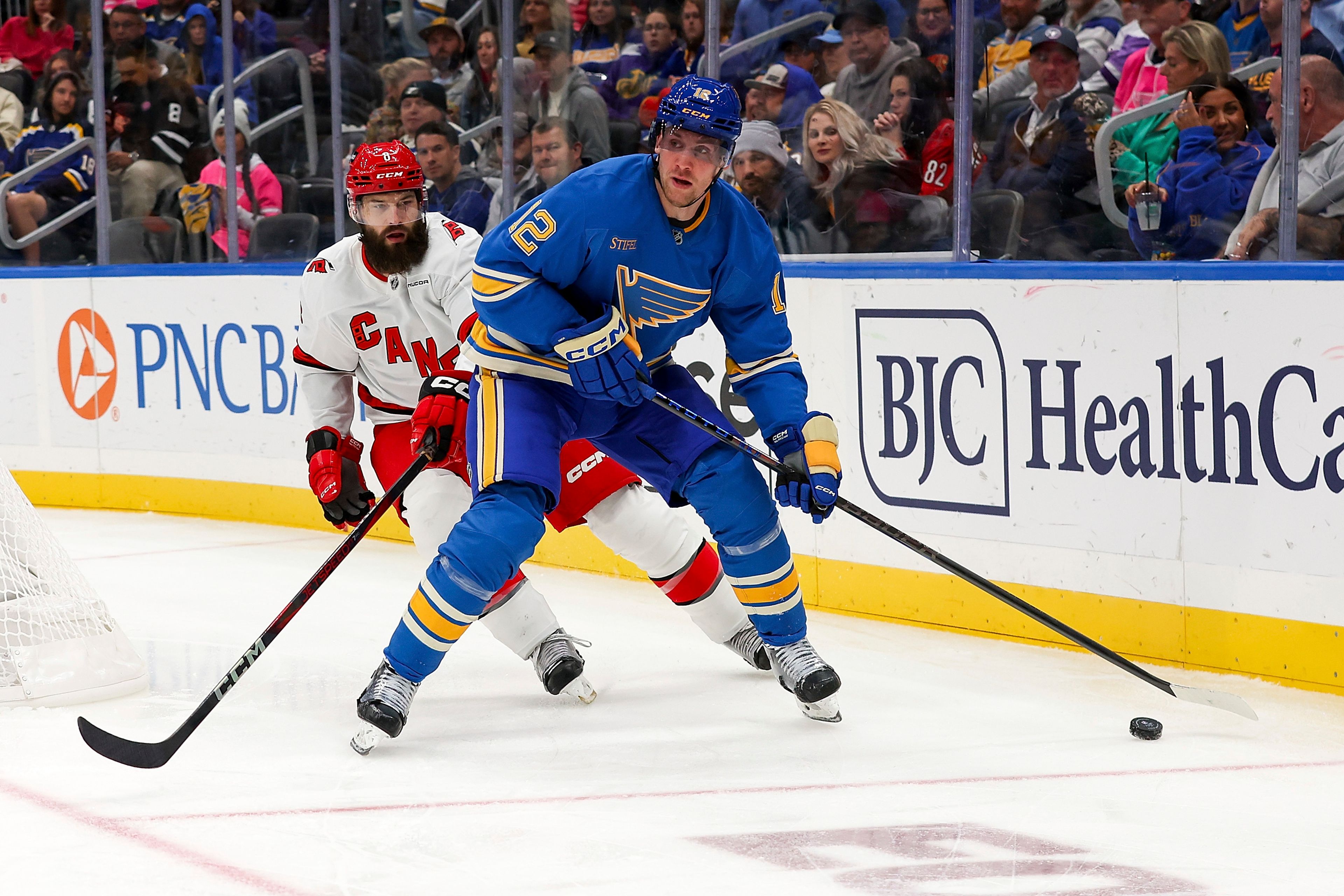 St. Louis Blues' Radek Faksa (12) controls the puck while under pressure from Carolina Hurricanes' Brent Burns (8) during the second period of an NHL hockey game Saturday, Oct. 19, 2024, in St. Louis. (AP Photo/Scott Kane)