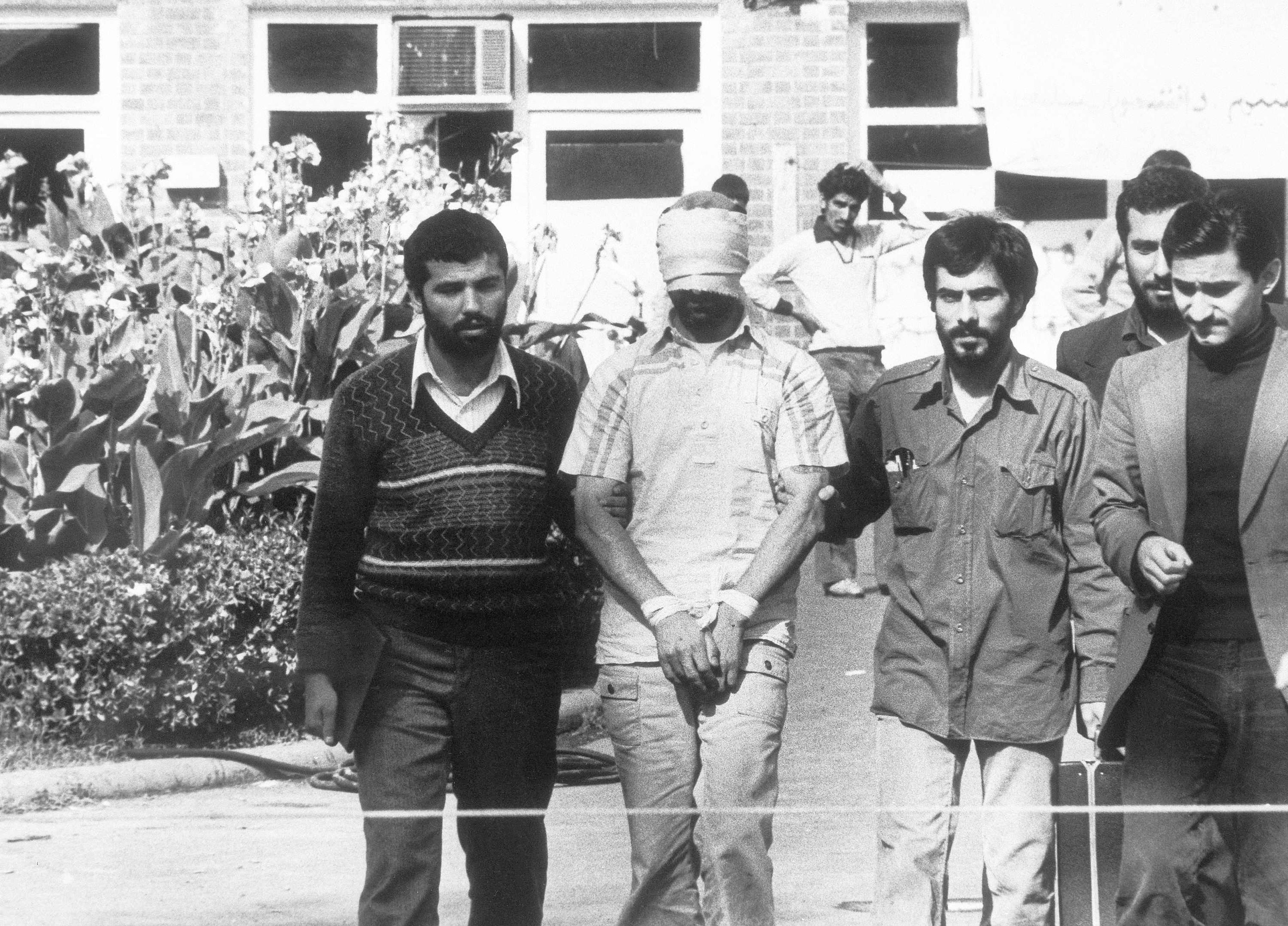 Blindfolded and hands bound, one of the hostages held at the U. S. Embassy in Tehran, Iran, is shown to the crowd by Iranian students Nov. 8, 1979. 