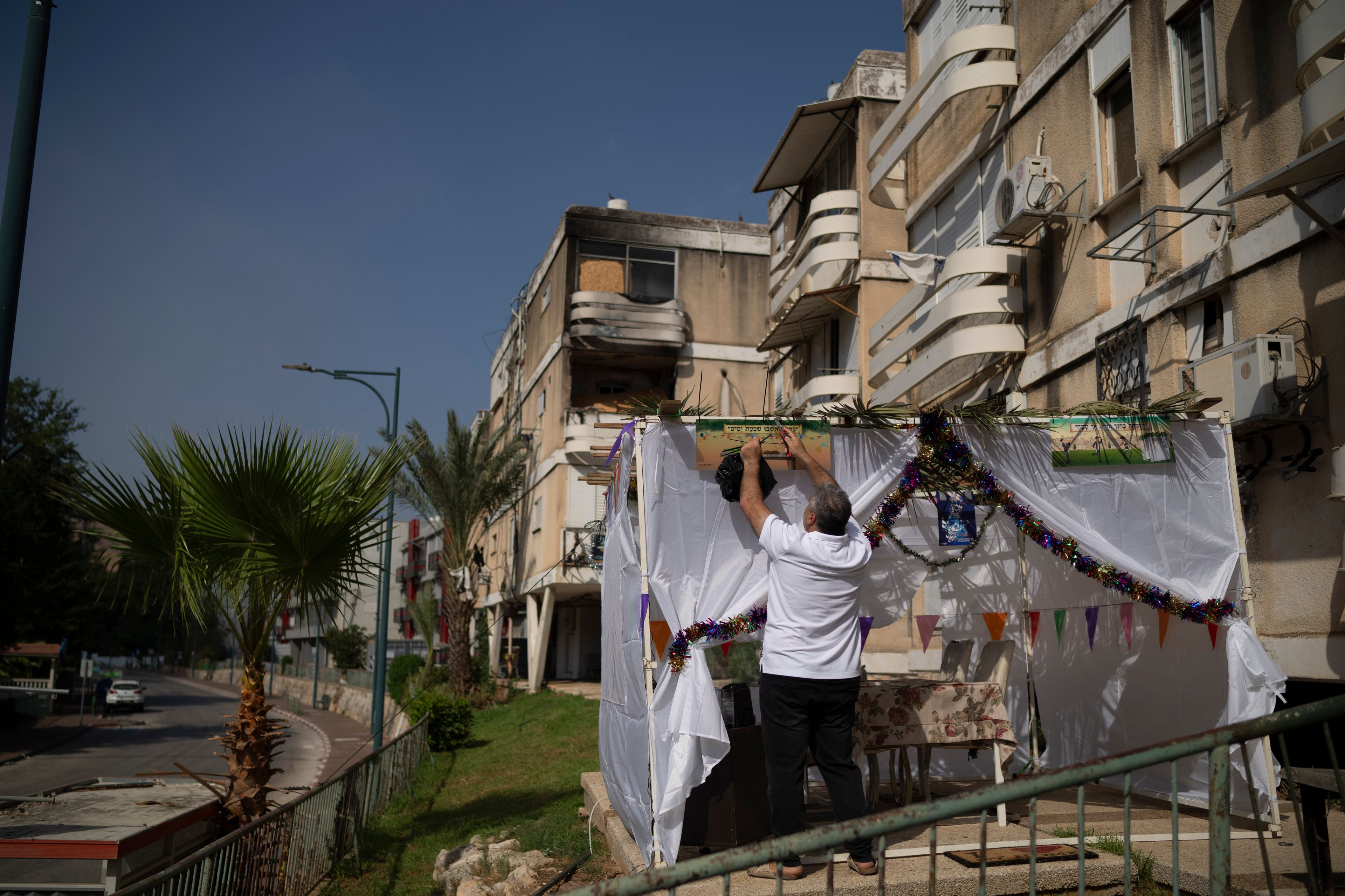 Zavik Zoigi checks the Sukkah, a temporary hut built for the Jewish holiday of Sukkot, placed in front of his residence ahead the weeklong holiday celebrations in Kiryat Shmona, a town located neart to the border with Lebanon, in northern Israel, Tuesday, Oct. 15, 2024. (AP Photo/Leo Correa)