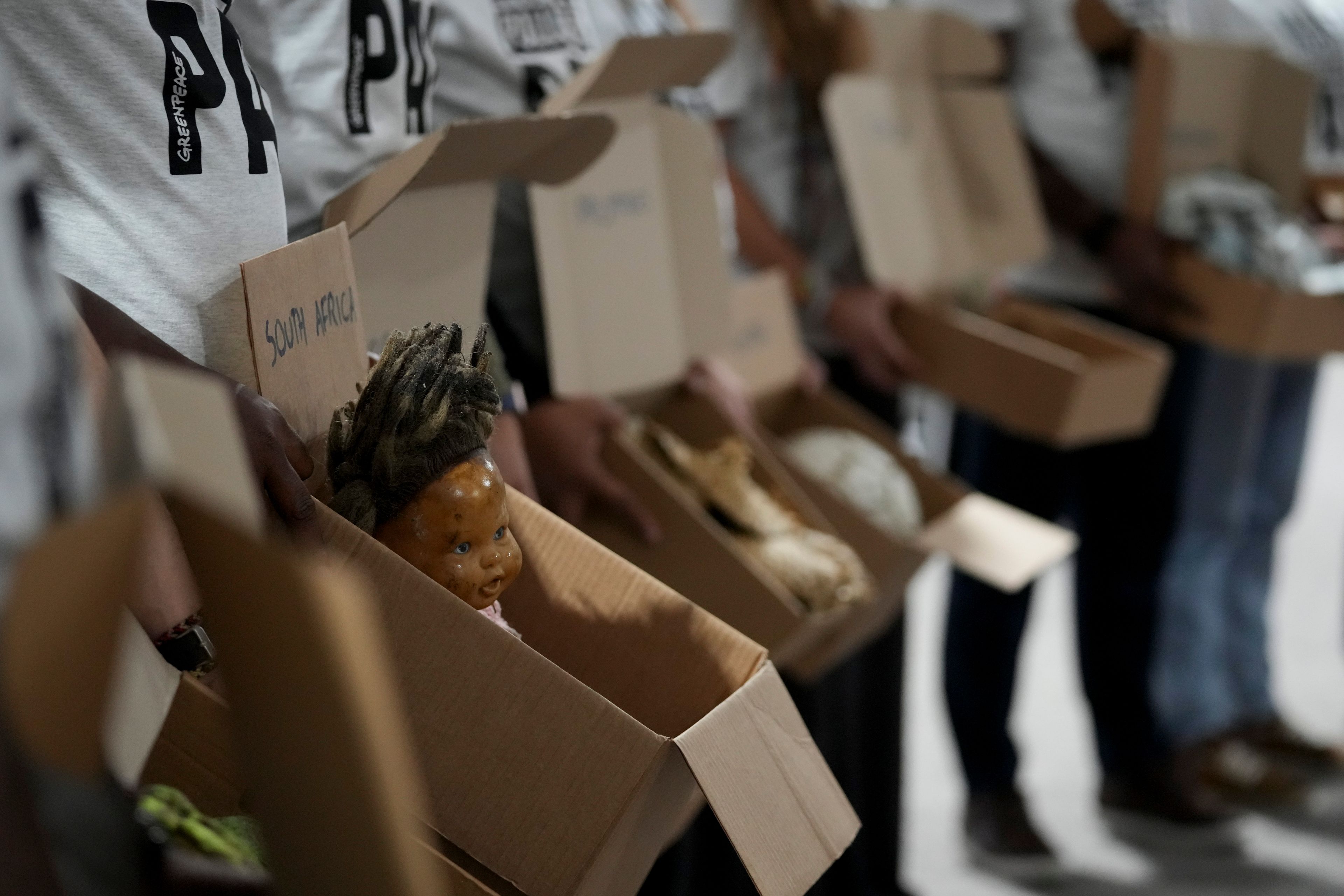 Demonstrators wearing shirts that say "make polluters pay" hold items that were recovered by support teams from extreme weather events and displayed at the COP29 U.N. Climate Summit, Monday, Nov. 18, 2024, in Baku, Azerbaijan. (AP Photo/Sergei Grits)