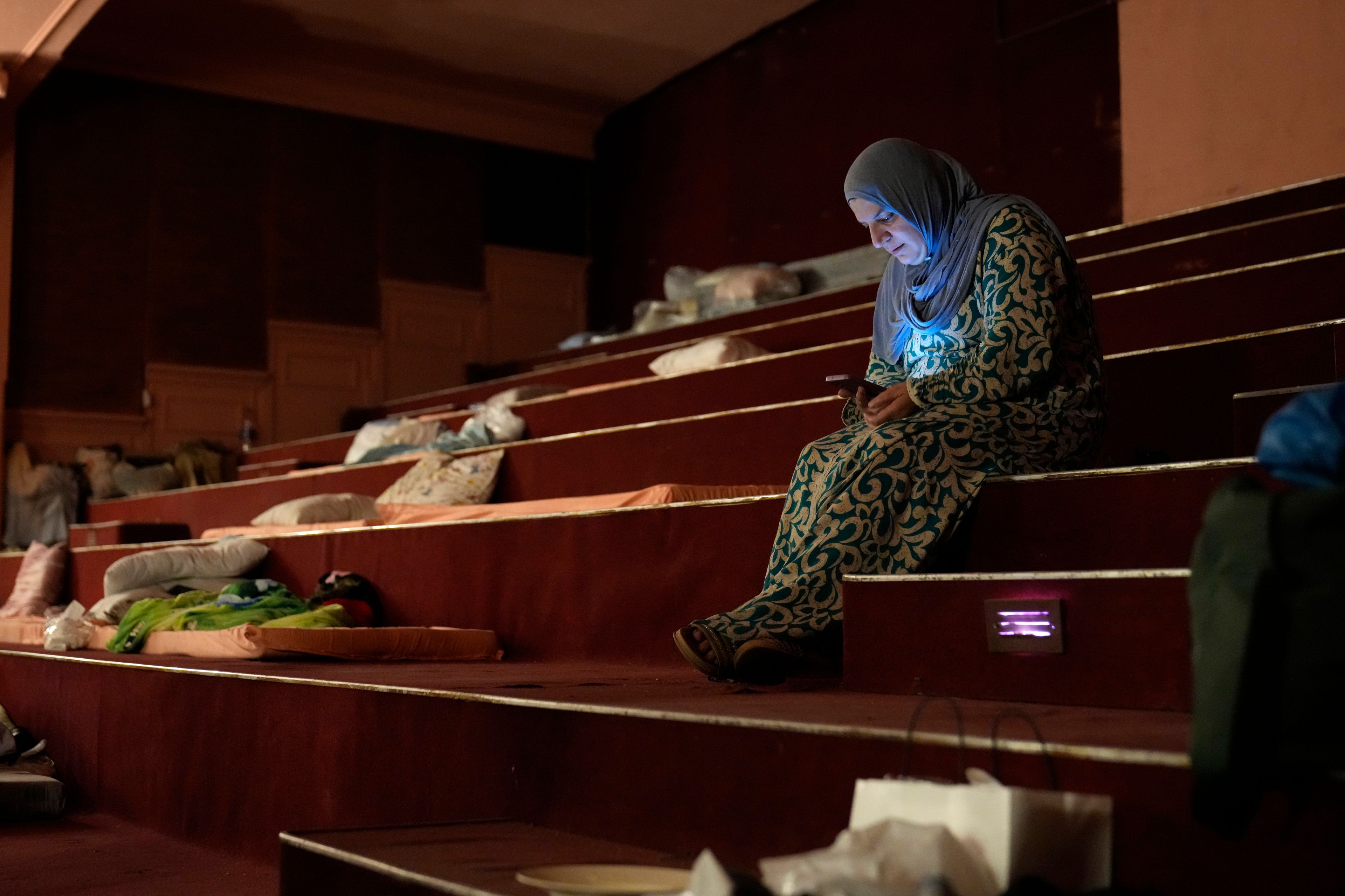 Mona Hanafi, a Lebanese displaced woman who fled the ongoing Hezbollah-Israel war in south Lebanon, looks at her mobile phone inside one of Beirut's oldest and best known movie theatres, Le Colisee, where she is sheltering with her family, in Beirut, Lebanon, Tuesday, Oct. 22, 2024. (AP Photo/Hussein Malla)