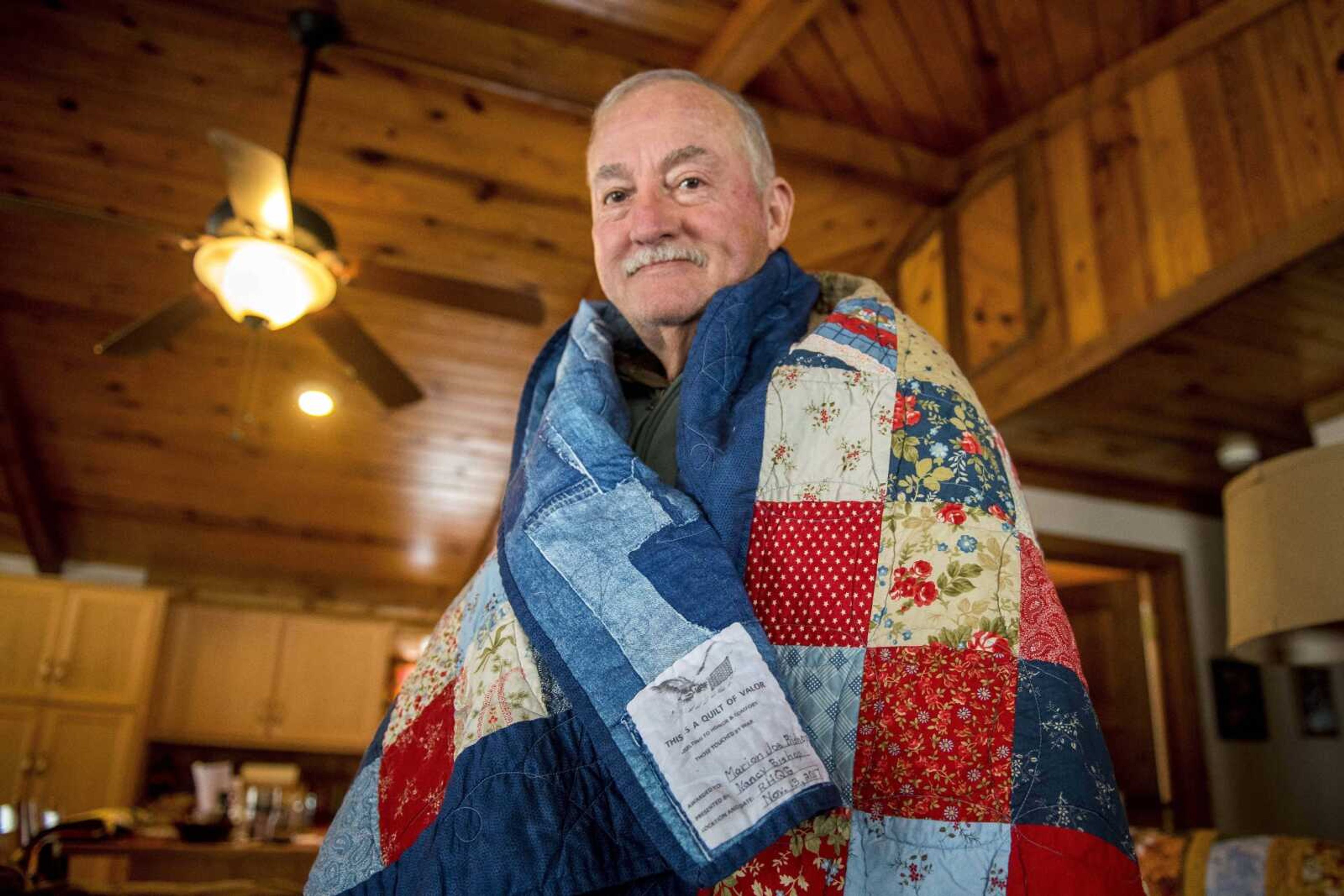 U.S. Navy veteran Joe Bishop with a Quilt of Valor his wife, Nancy, and granddaughter, Marah Brown, made for him in 2018.