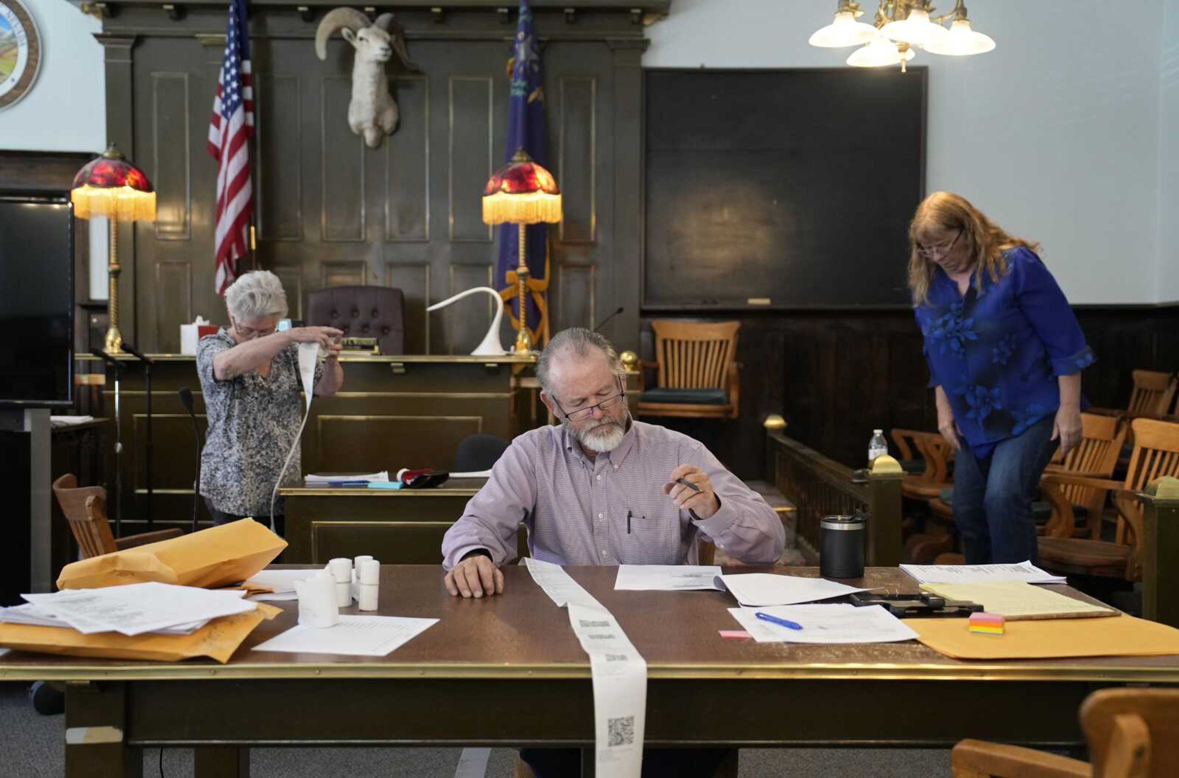 Esmeralda County Commissioner Ralph Keyes, center, works on a hand recount of votes with others, June 24 in Goldfield, Nevada. An AP survey shows the majority of candidates running this year for the state posts that oversee elections oppose the idea of hand counting ballots, a laborious and error-prone process that has gained favor among Republicans who have been inundated with unfounded voting machine conspiracy theories.