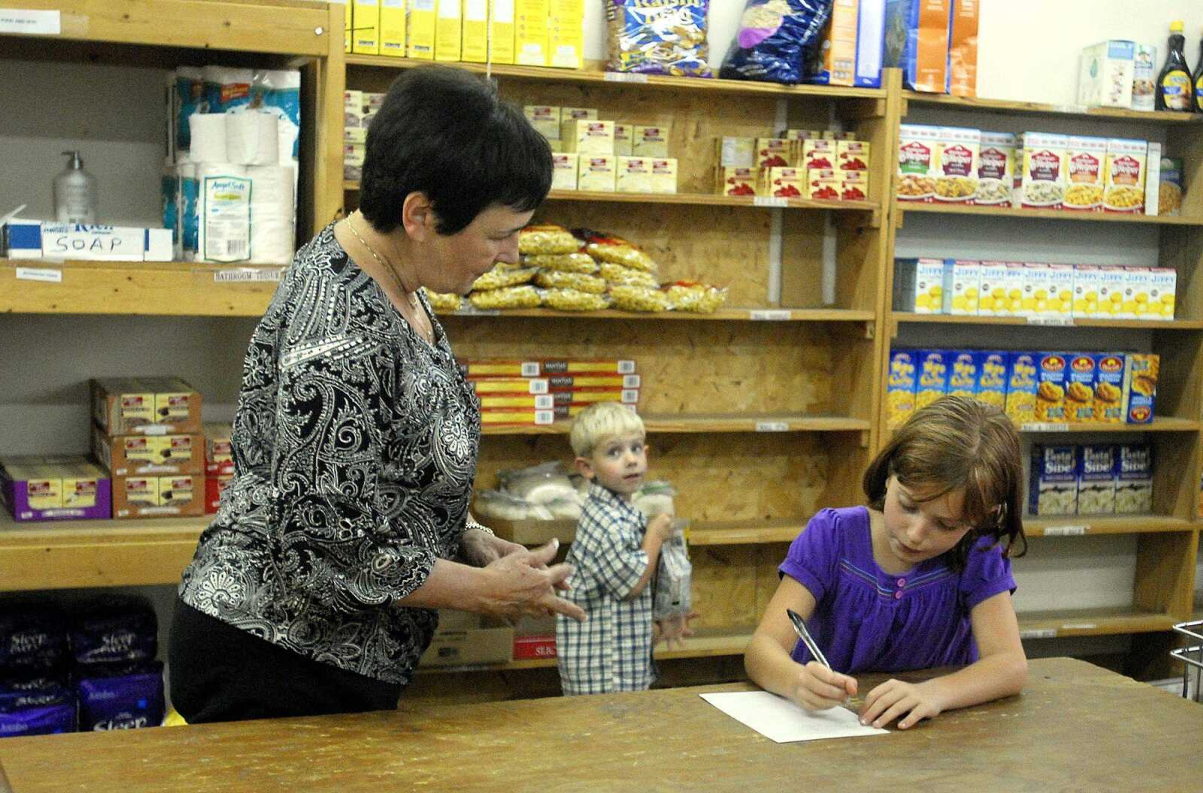 Diane Shafer helps Samantha, 7, and William, 4, make out a shopping list for the FISH food pantry Friday in Cape Girardeau. Samantha and William donated $113 that went to purchase supplies for the pantry. (Laura Simon)