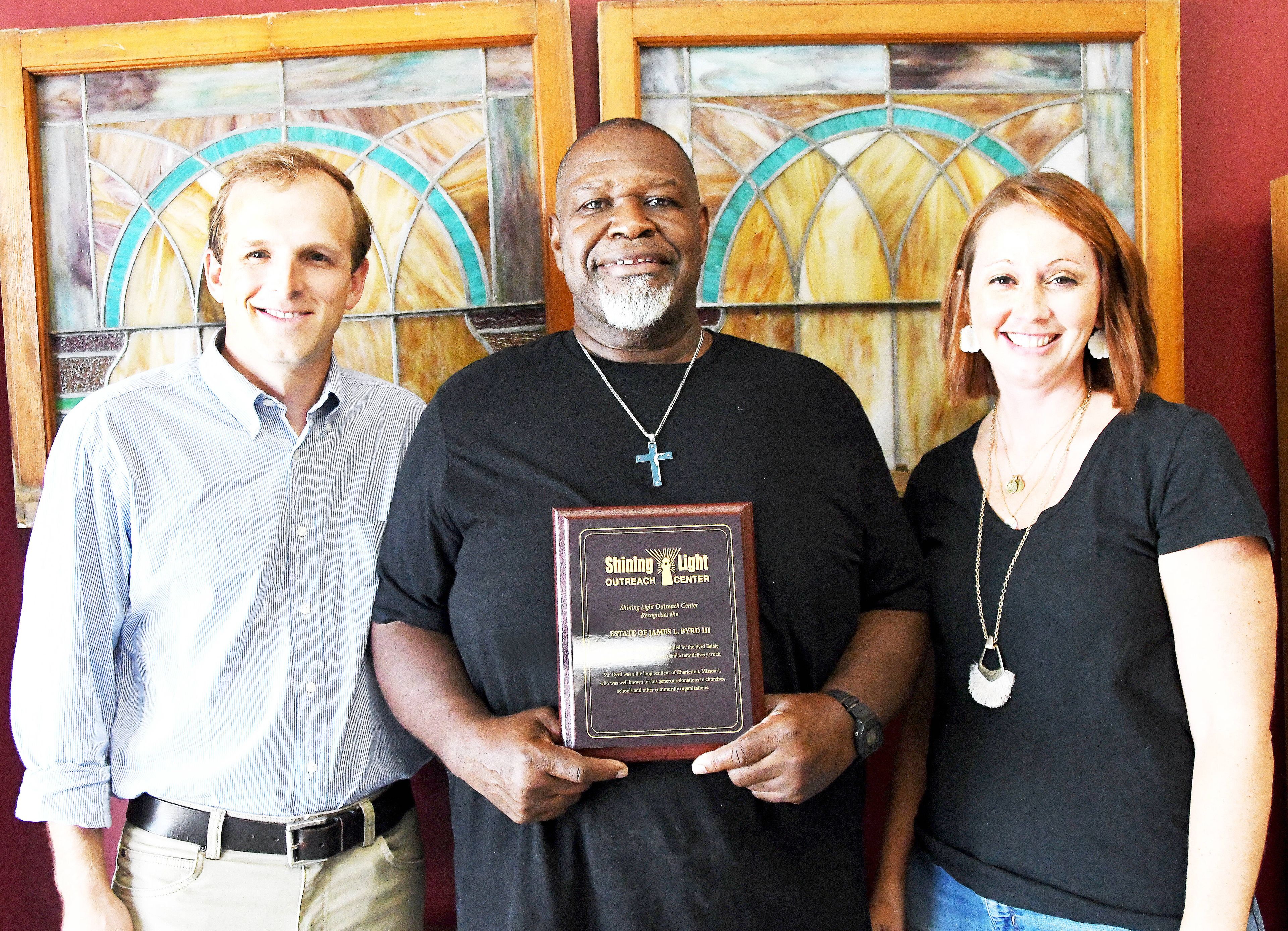 Pictured from left are Hudson Byrd, Glenn Fennell Sr., executive director of the Shining Light Outreach Center, and Alana Mills, administrative assistant at the Center, with a plaque recognizing the James L. Byrd Estate for its gift to the Center. The estate provided funds for a new freezer and new truck which will be used in the Center's effort to provide food to area residents. 
