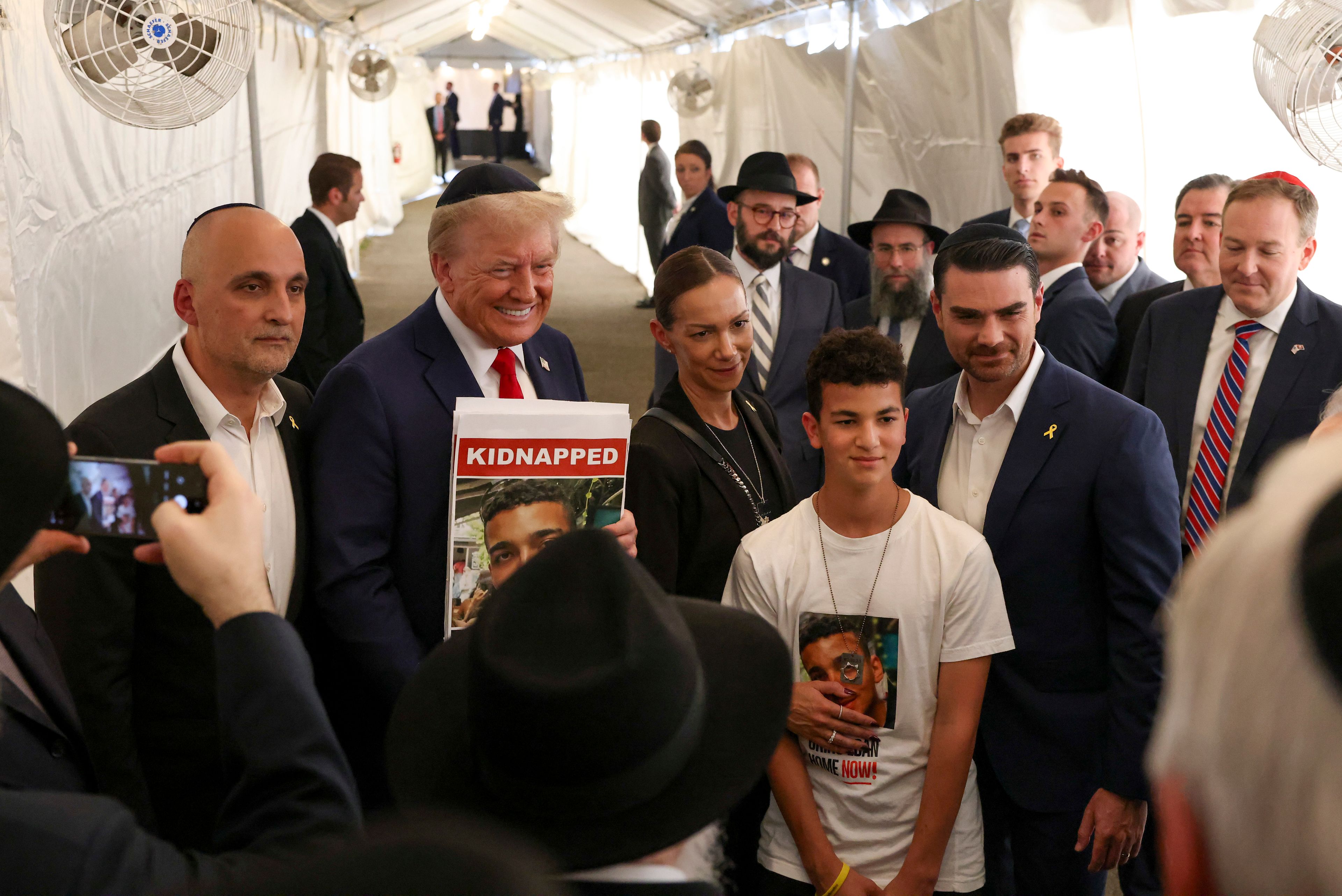 Republican presidential nominee former President Donald Trump poses for photos with family members of Edan Alexander, a hostage held by Hamas, after visiting the gravesite of Rabbi Menachem Mendel Schneerson, Monday, Oct. 7, 2024, in New York. (AP Photo/Yuki Iwamura)