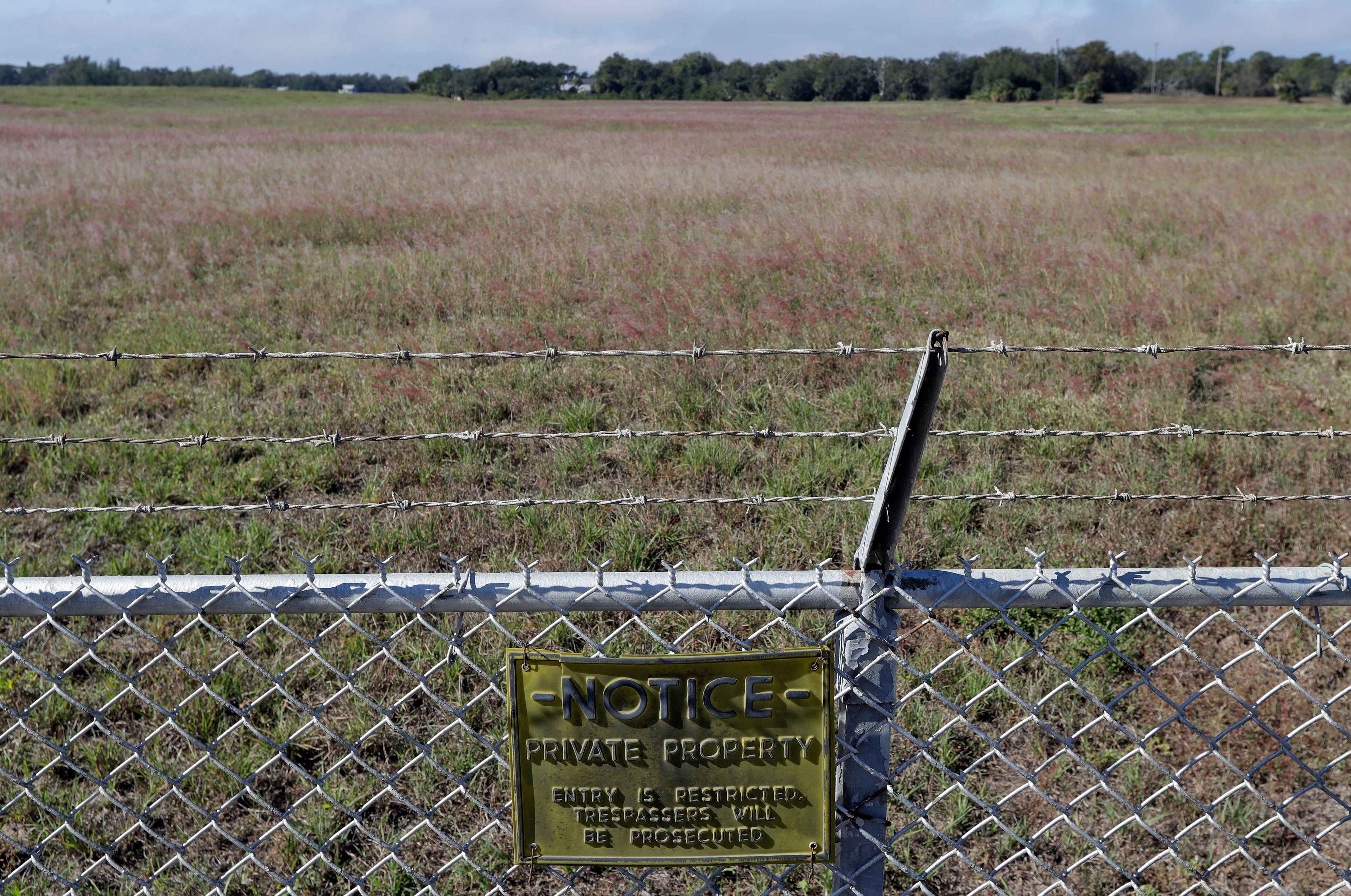 FILE - A private property sign is attached to a fence outside the old Stauffer chemical plant toxic waste dump site in Tarpon Springs, Fla., on Nov. 30, 2017. (AP Photo/Chris O'Meara, File)