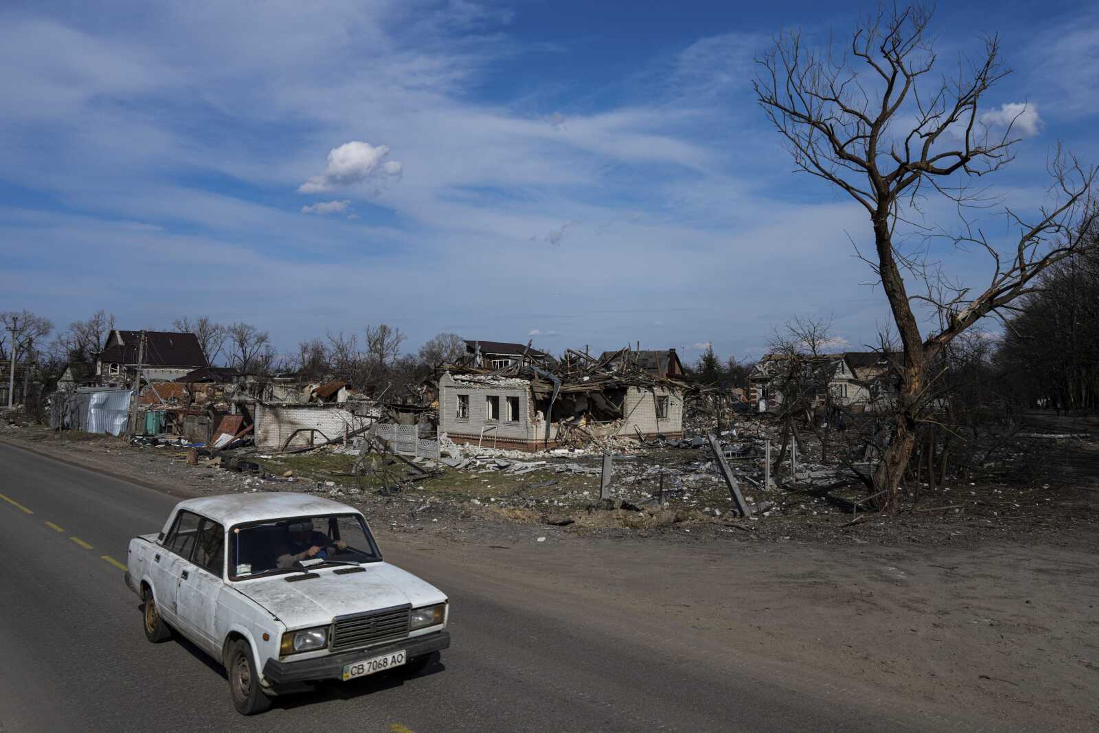 A car moves in a street past damaged houses Thursday in Chernihiv, Ukraine,. Ukraine is telling residents of its industrial heartland to leave while they still can after Russian forces withdrew from the shattered outskirts of Kyiv to regroup for an offensive in the country's east.