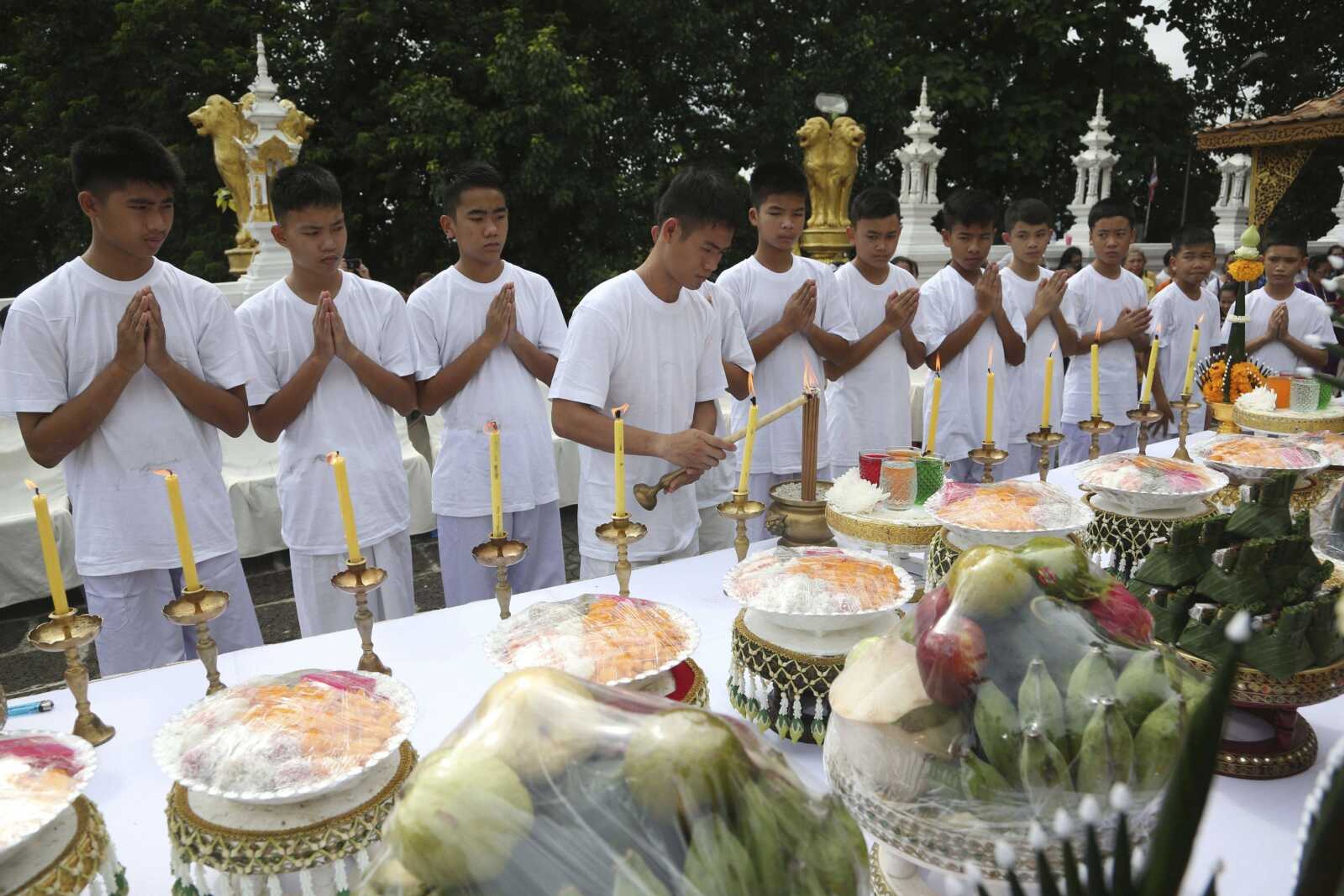 Soccer coach Ekkapol Chantawong, center, lights a candle as he and members of the rescued soccer team attend a Buddhist ceremony believed to extend the lives of its attendees as well as ridding them of dangers and misfortunes Tuesday in northern Thailand. The young soccer teammates and their coach who were trapped in a Thai cave have attended a Buddhist ceremony as they prepare to be ordained to become Buddhist novices and monks.