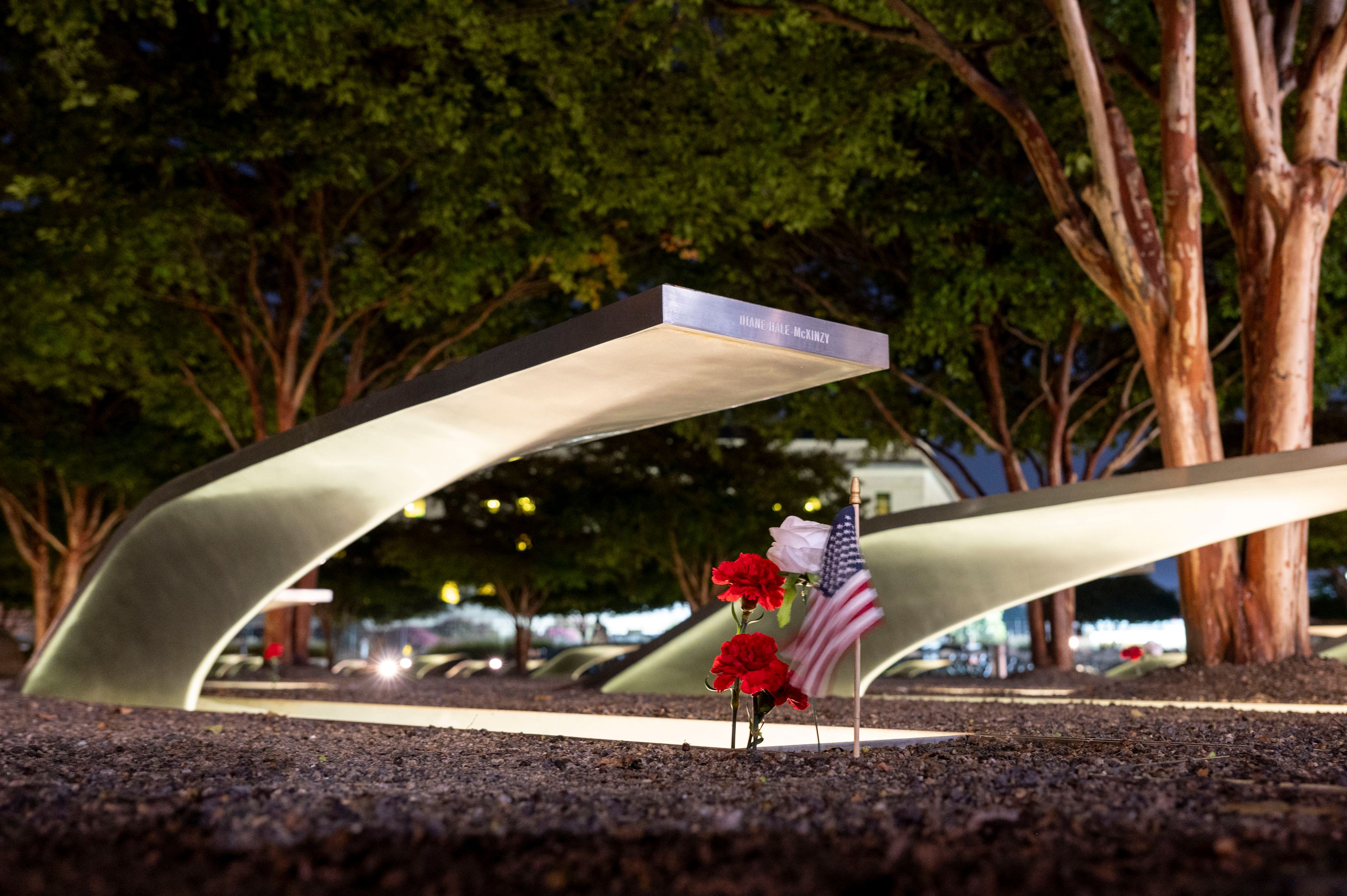 Flowers and a flag adorn one of the memorial benches outside the Pentagon before the start of a dawn 9/11 remembrance ceremony on Wednesday, Sept. 11, 2024 in Washington. (AP Photo/Kevin Wolf)