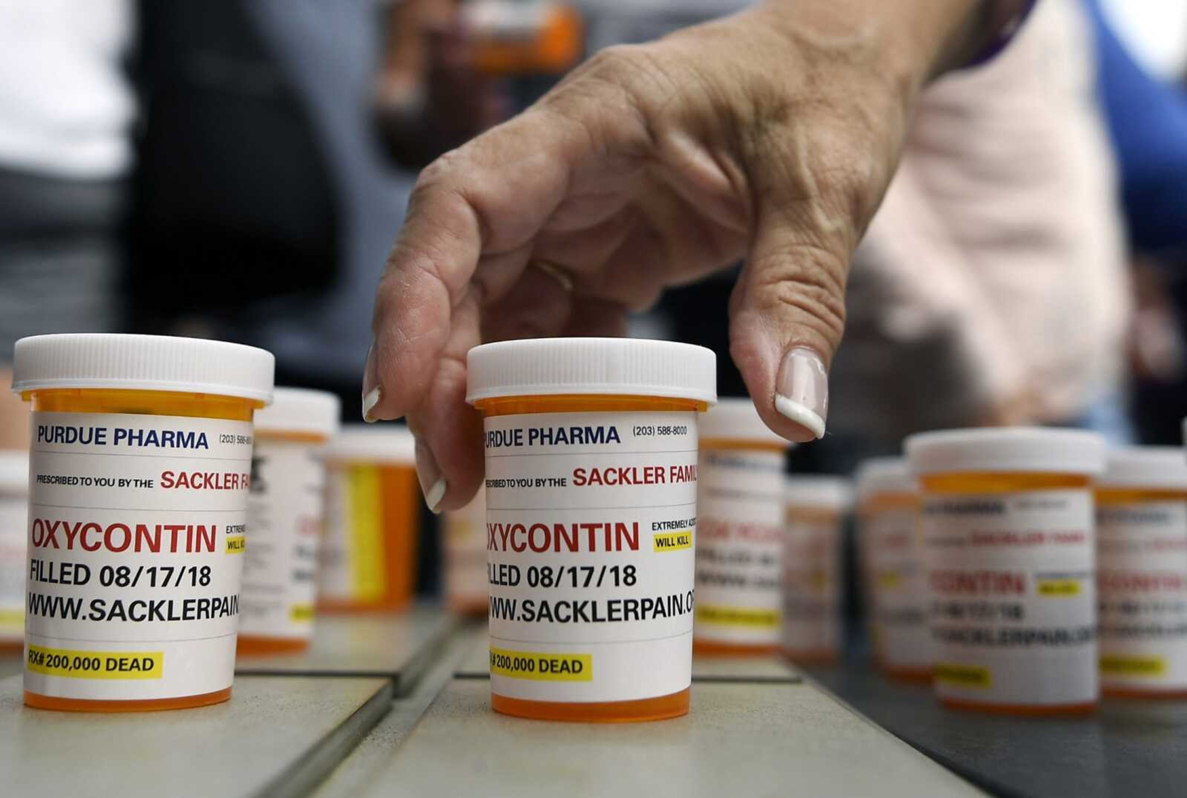 Family and friends who have lost loved ones to OxyContin and opioid overdoses leave pill bottles in protest outside the headquarters of Purdue Pharma, which is owned by the Sackler family, Aug. 17 in Stamford, Connecticut.