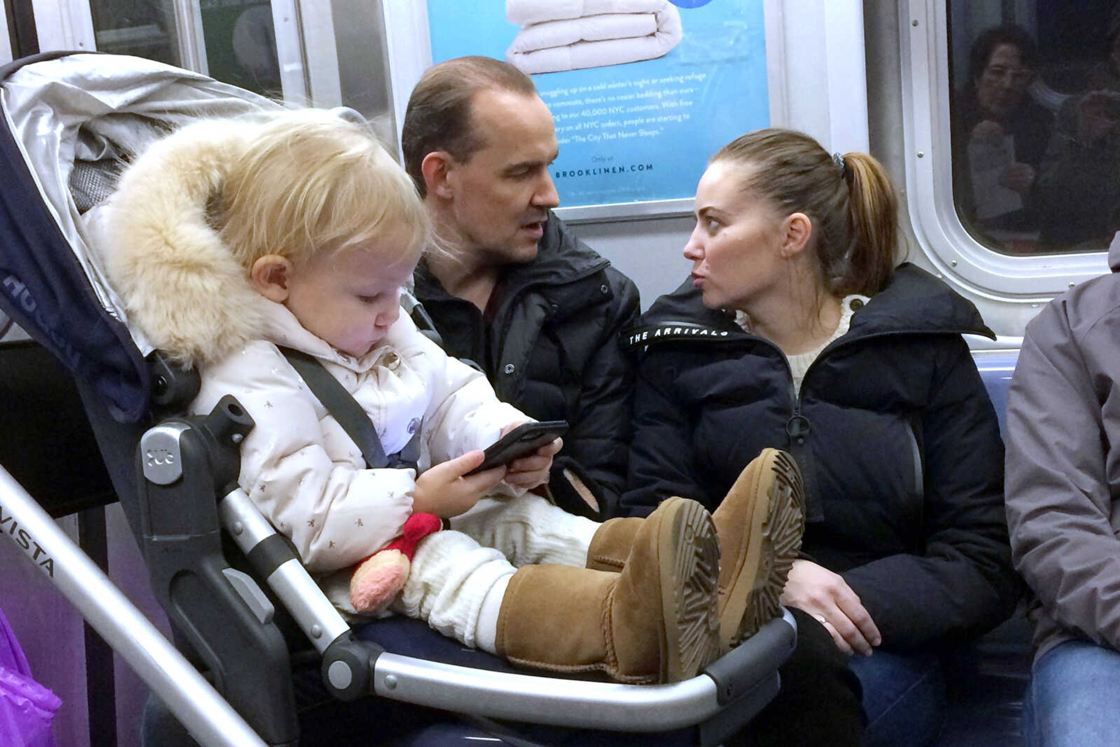 A baby girl plays with a mobile phone while riding in a New York subway Dec. 17.